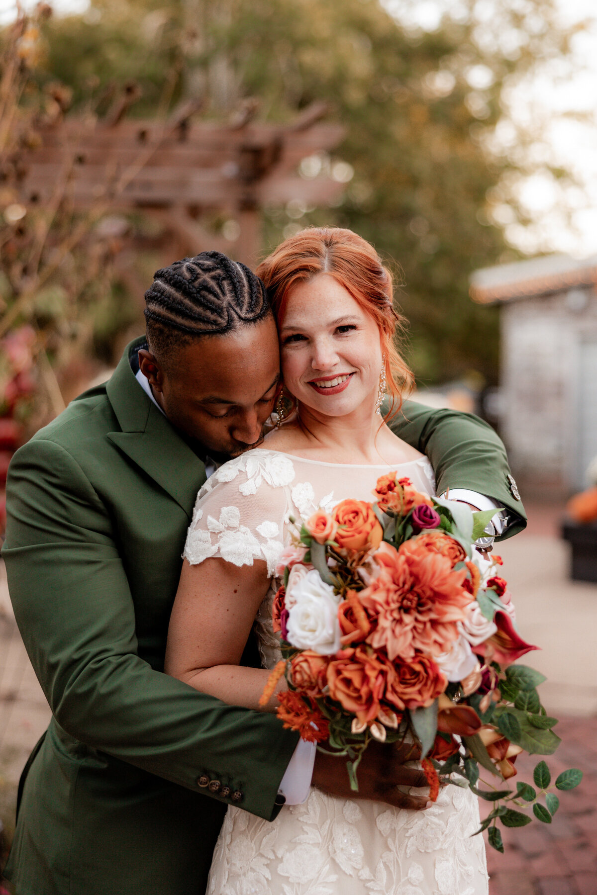 A man kisses his wifes shoulder during wedding portraits at Blumen Gardens.