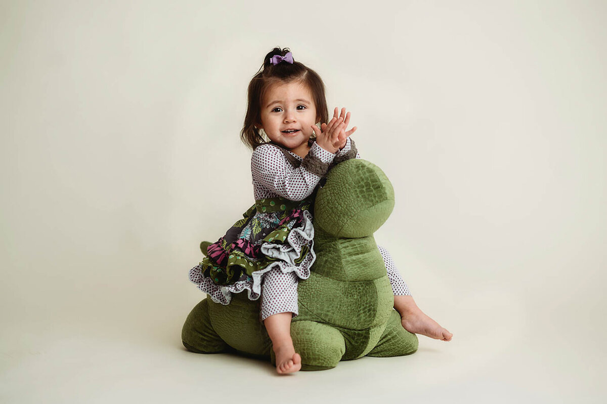 Baby rides on a dinosaur during  her Cake Smash Photoshoot in Asheville, NC.