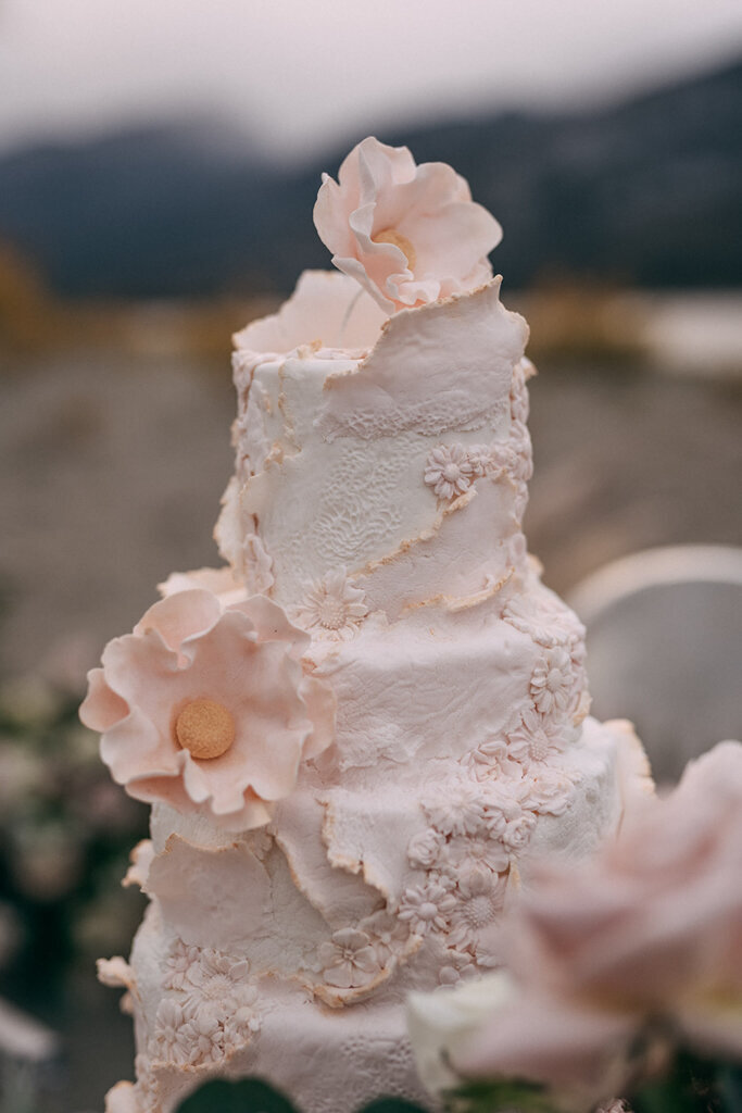 Unique textured four-tiered textured pink wedding cake, covered in intricate floral details and sugar flowers, created by Chartier YYC, elegant cakes & desserts in Calgary, AB, featured on the Brontë Bride Vendor Guide.