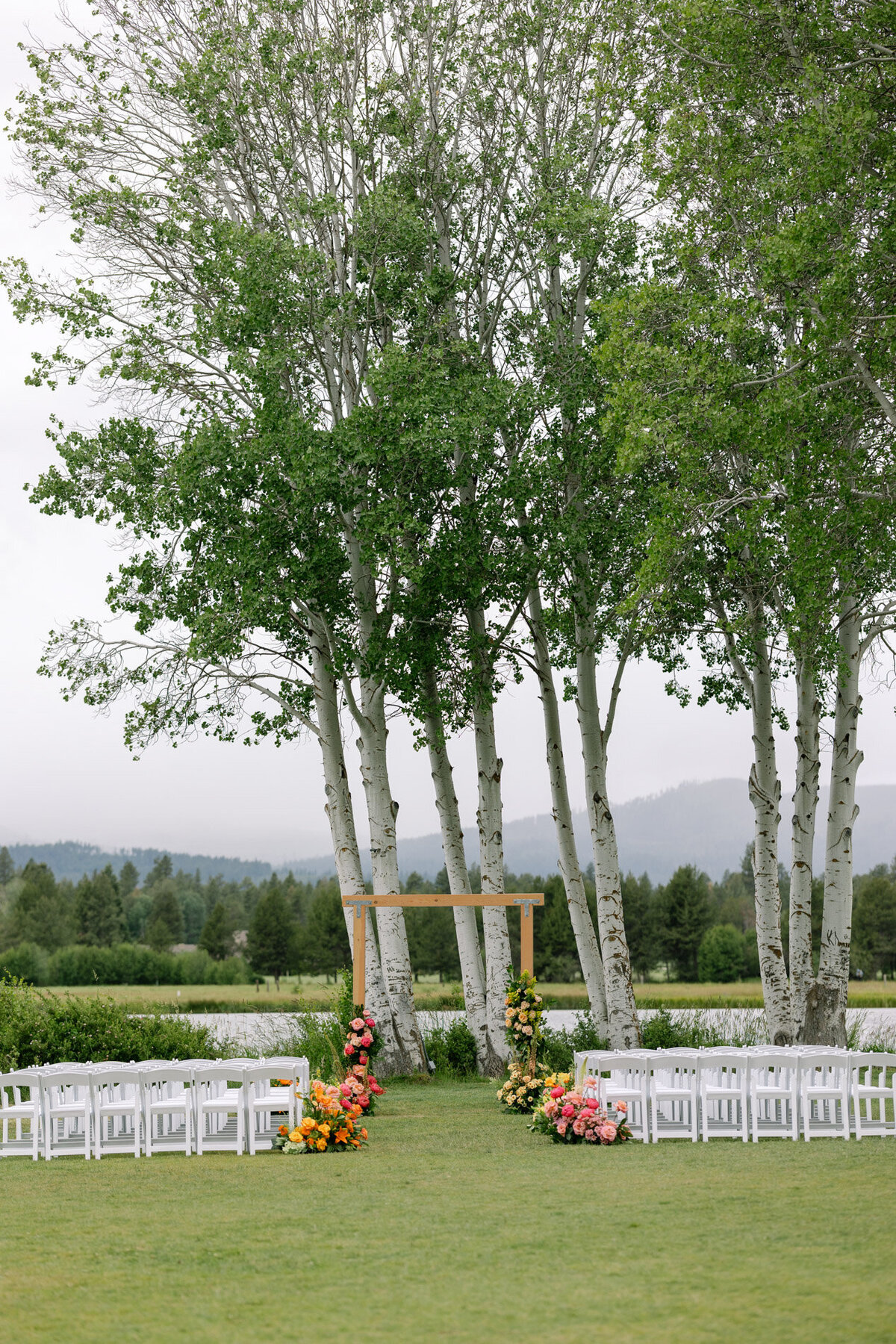 Oregon wedding ceremony setup with views of the sisters mountains, trees and florals in the aisle representing full service design and calligraphy by Life in Letters.