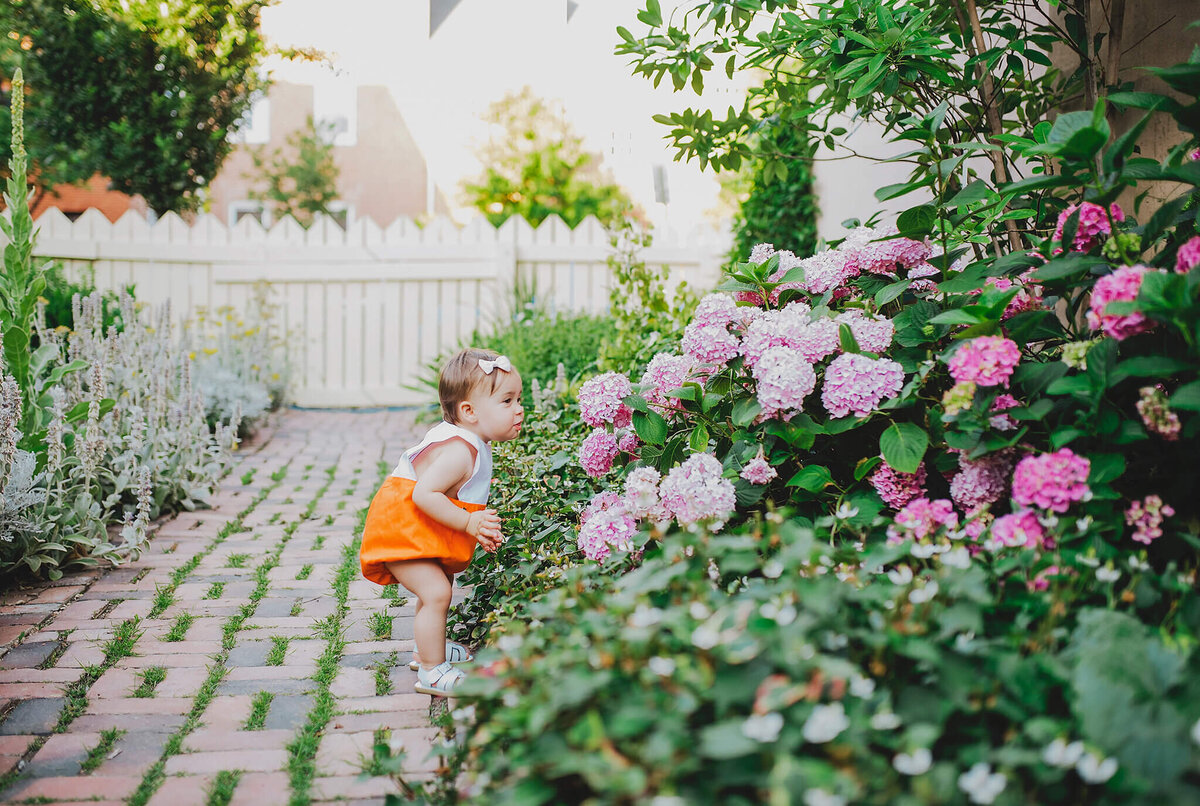 Baby girl in orange shorts in a garden in Fells Point Baltimore Maryland