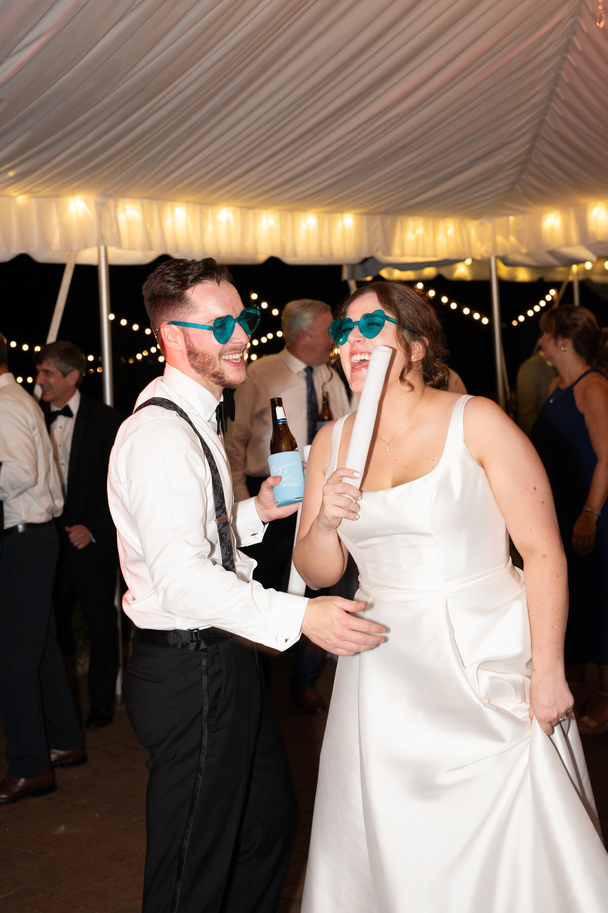 A wedding couple dancing and laughing while wearing colored glasses