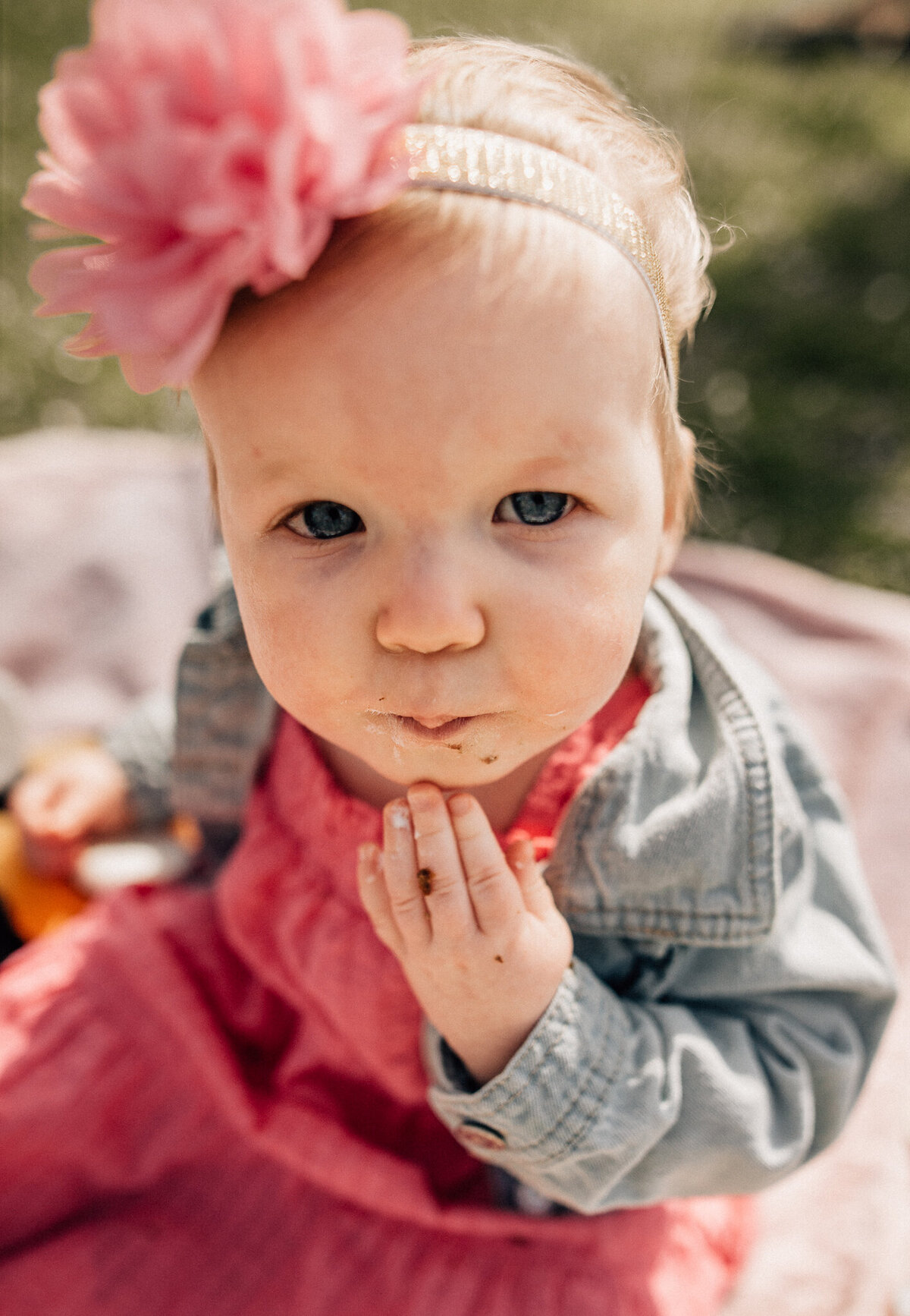 Baby eats food and looks at camera.