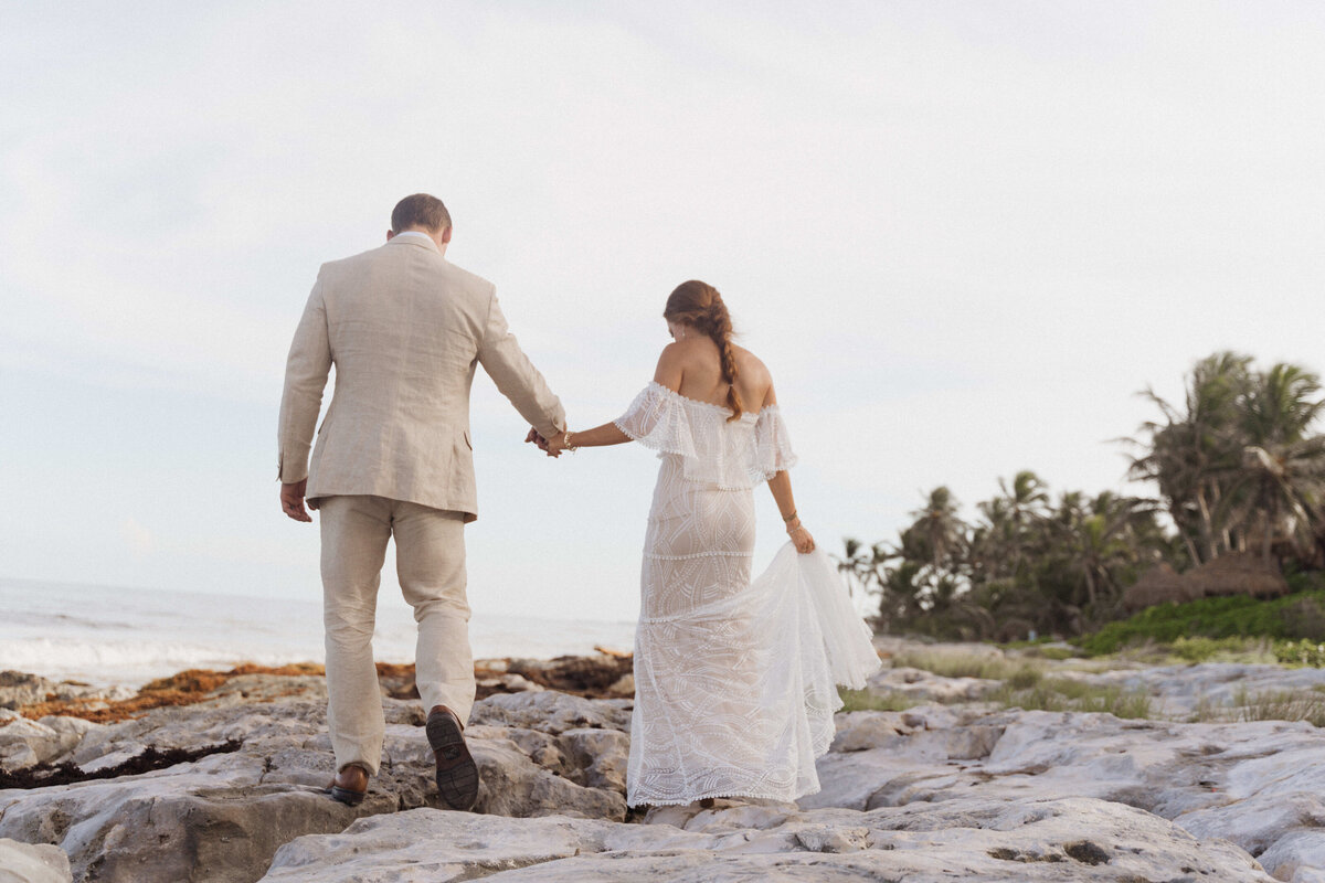 Couple taking a stroll over the bali coast covered in rocks.