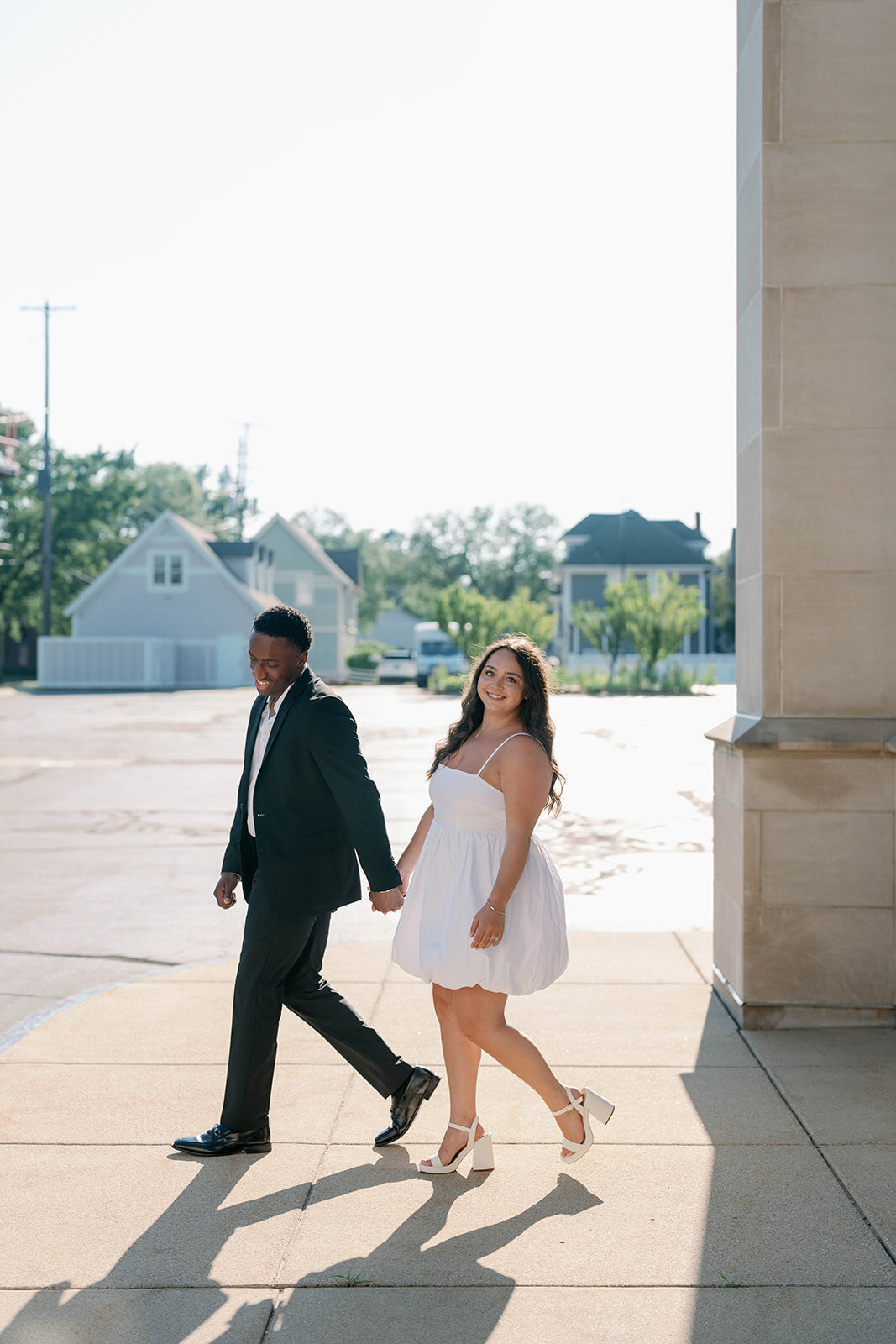 Silhouette-style engagement picture of couple walking along rooftop edge in Kalamazoo.