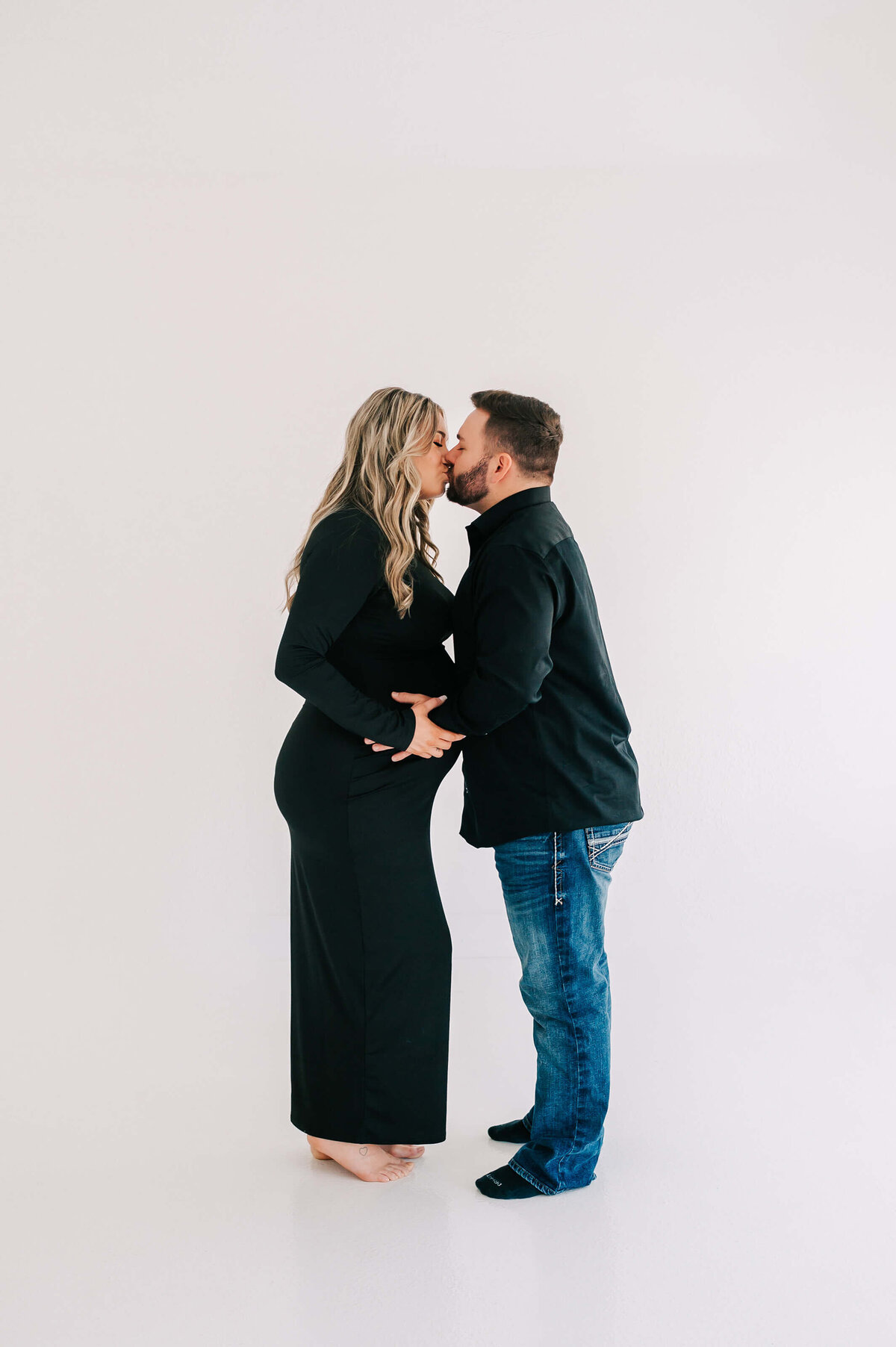 pregnant couple in black outfits kissing during Springfield MO maternity photography session