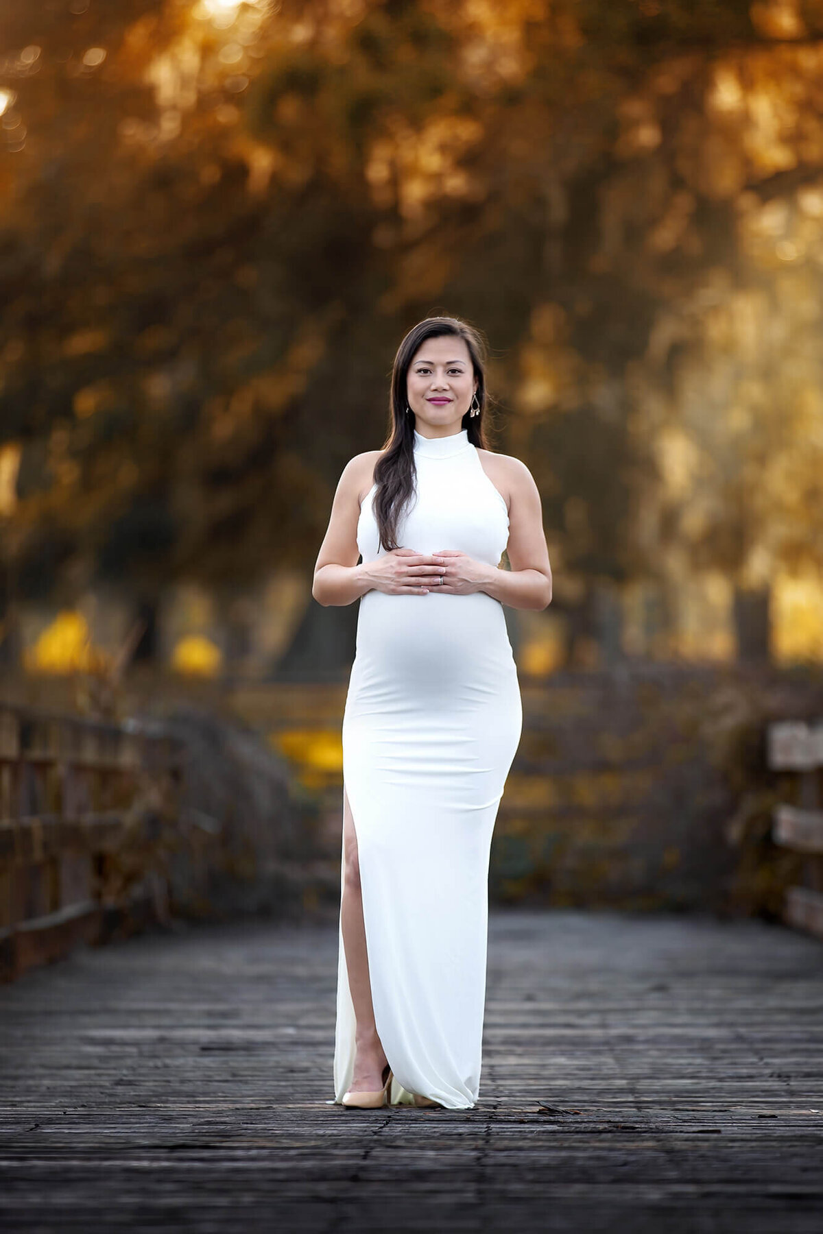 Elegant pregnant woman wearing a white, long, tight dress.