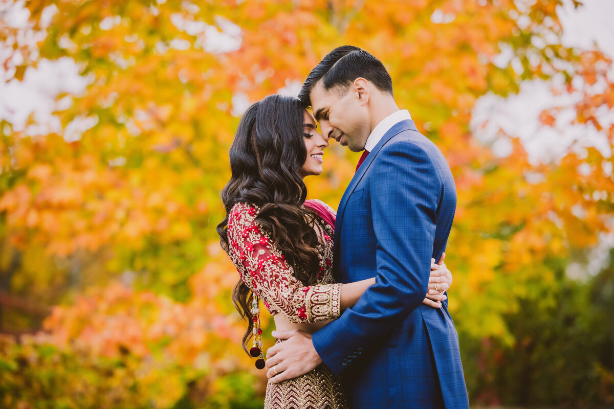 indian bride and groom embrace before their wedding reception in the fall at the marigold banquet in nj