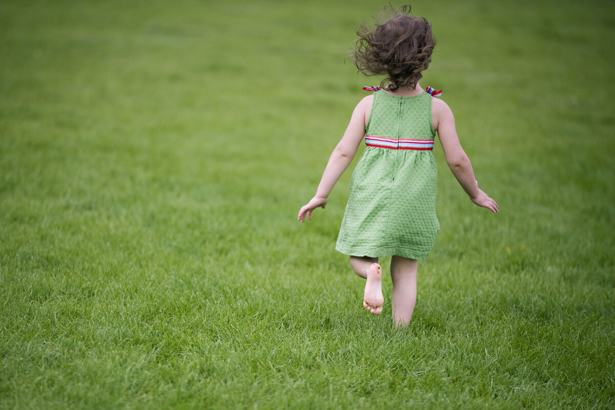 A girl runs through the grass in Hoboken. 