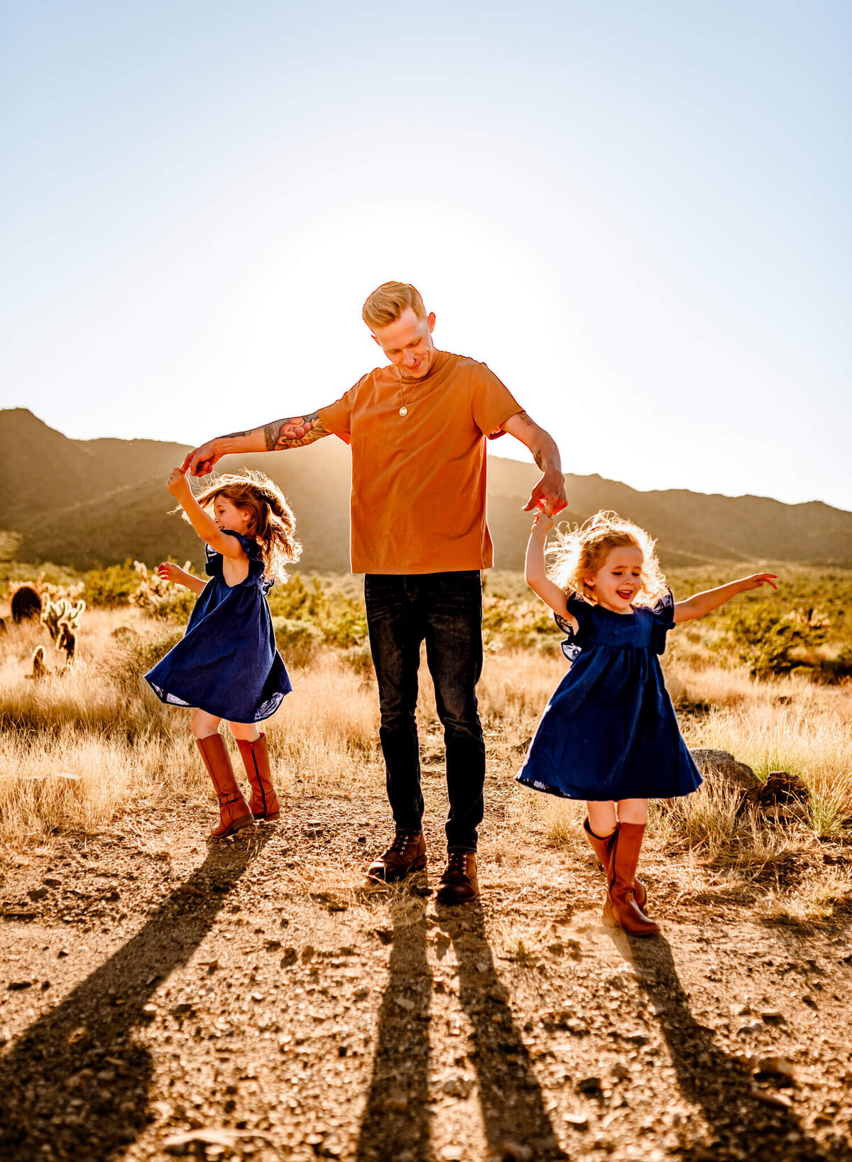 dad and daughters dancing in Arizona desert for family photography session with Amber Herrera