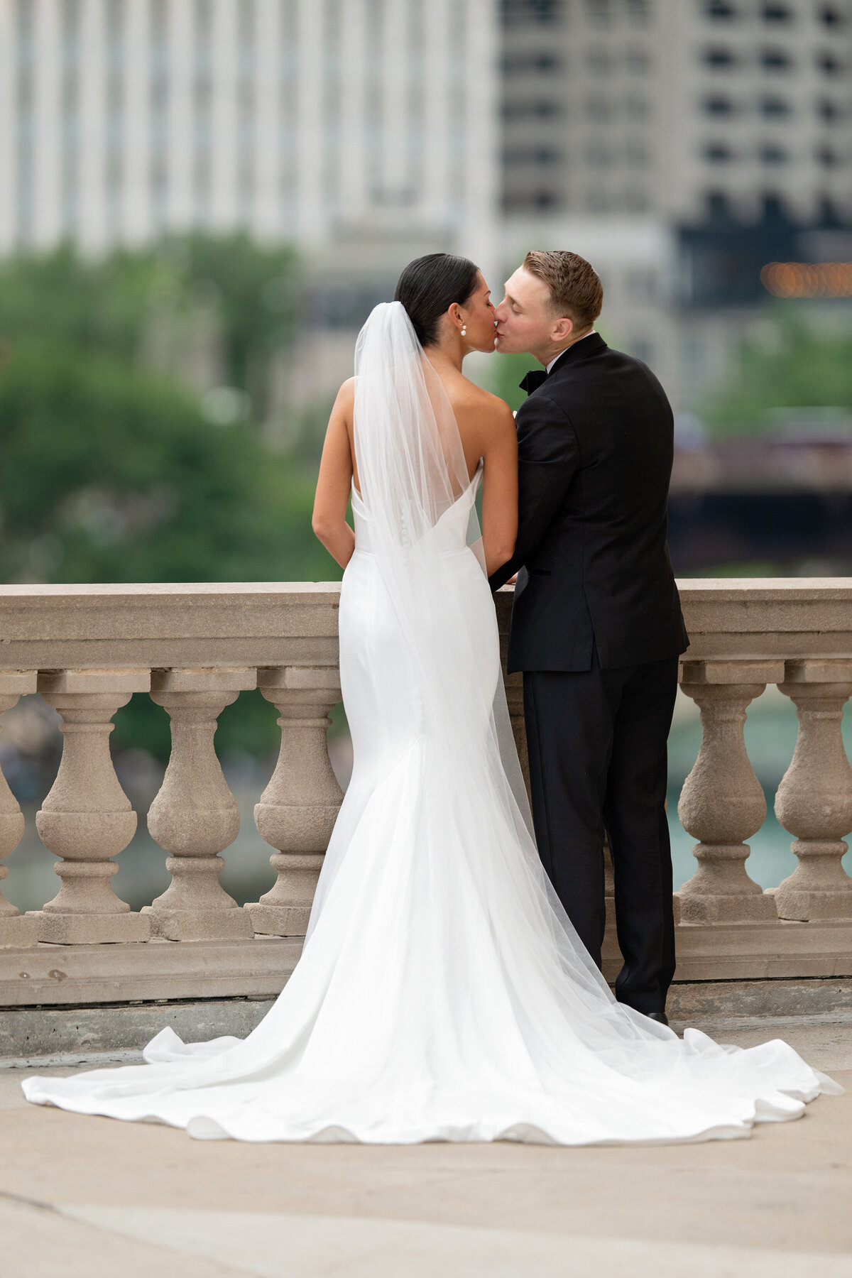 Bride and Groom kissing against pillar fence by Chicago river