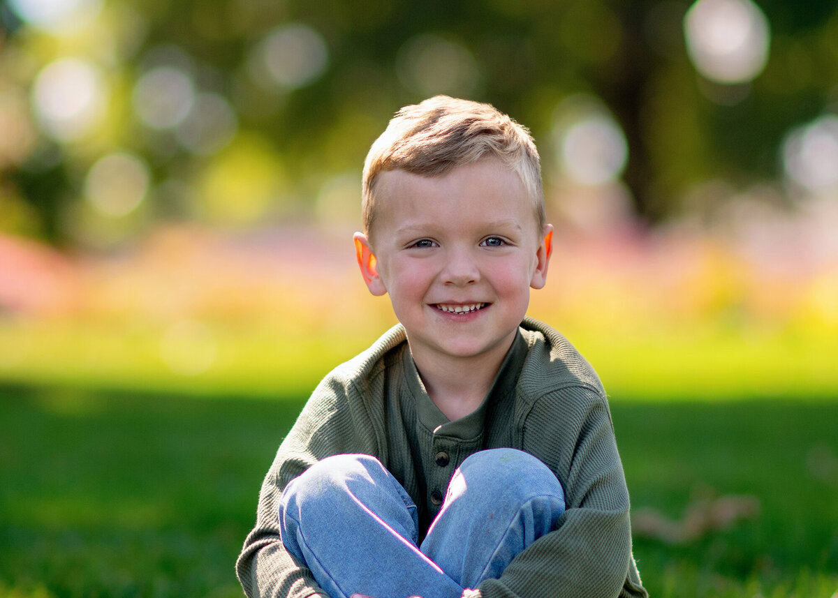 Close up of boy happily sitting with knees up in the grass