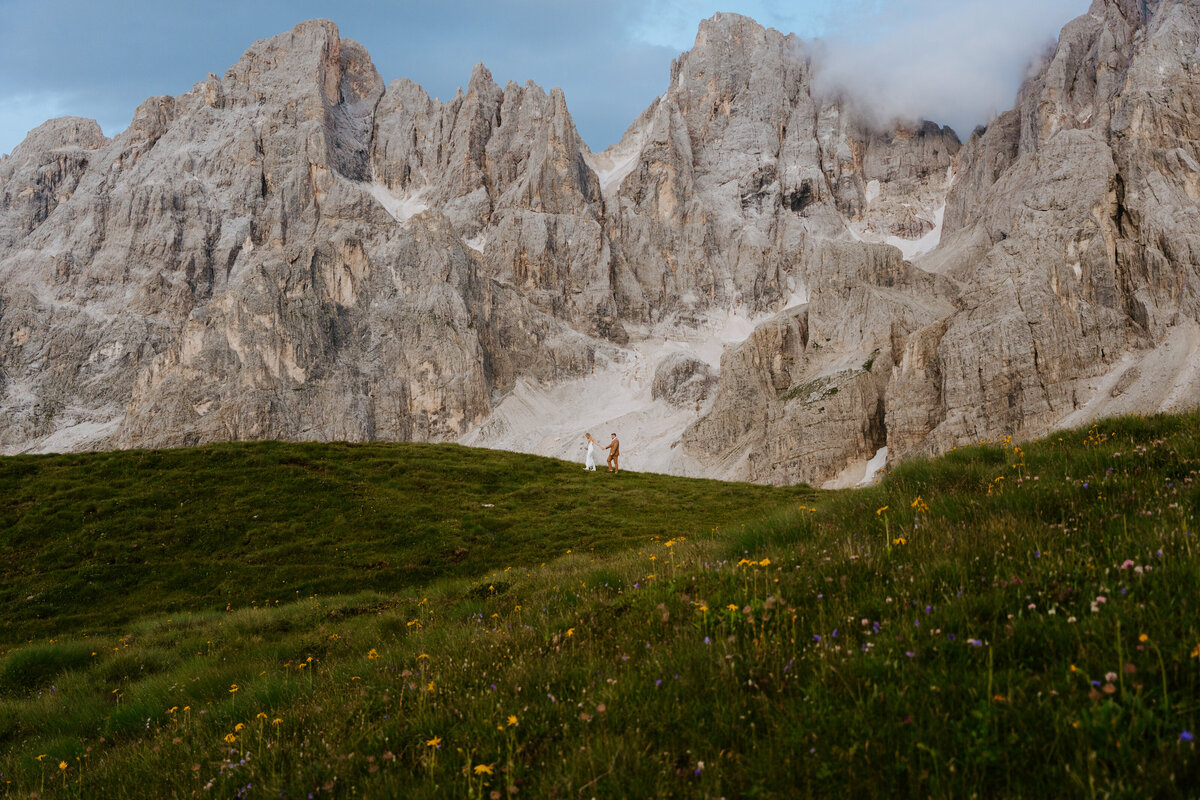 Couple walking beneath dramatic Dolomites peaks
