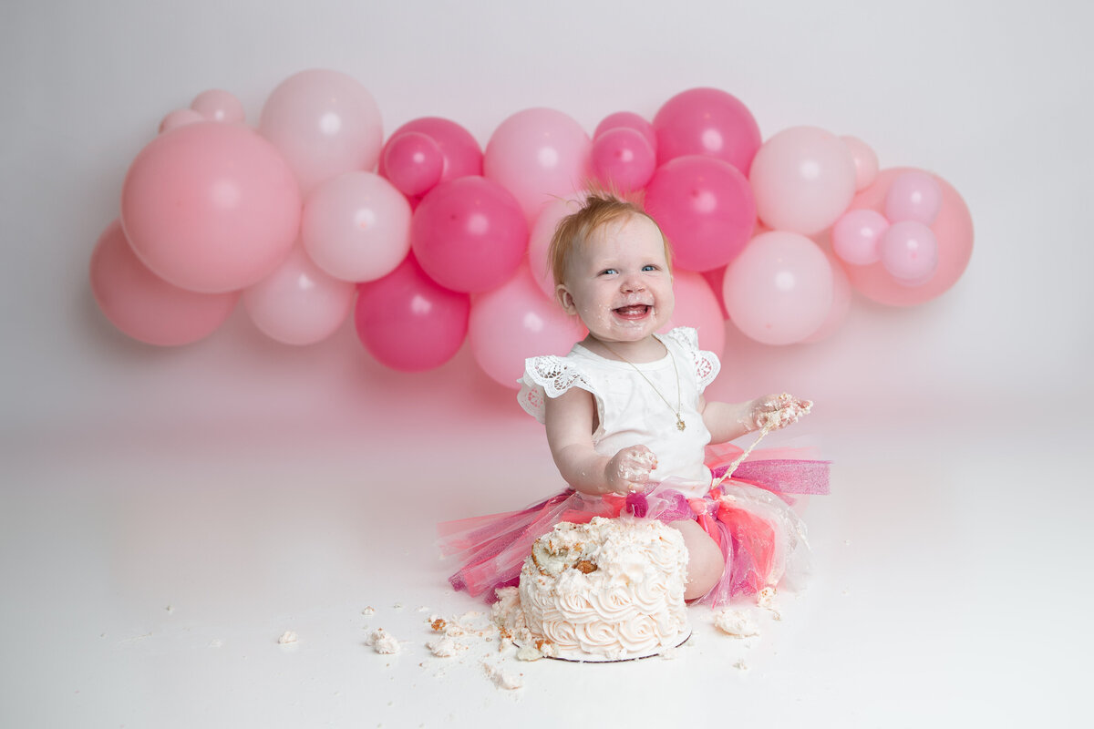 Pink cake with pink tutu and pink balloons first birthday cake smash