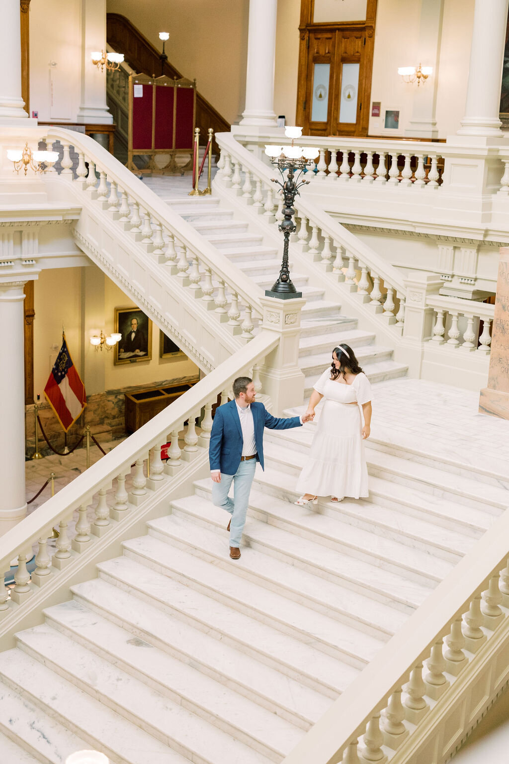 Man holds hands with finacee as she walks down steps of Athens City Hall