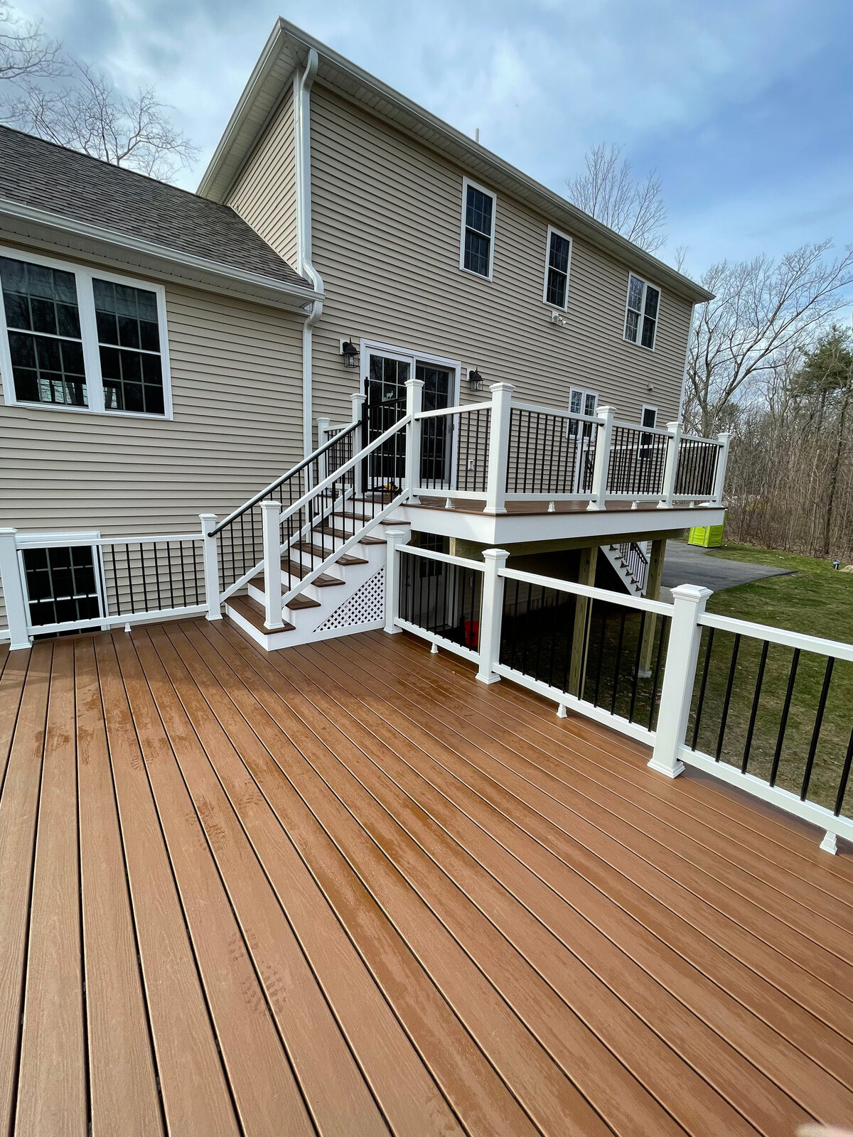 A brown two tier deck on a cream house with white stairs
