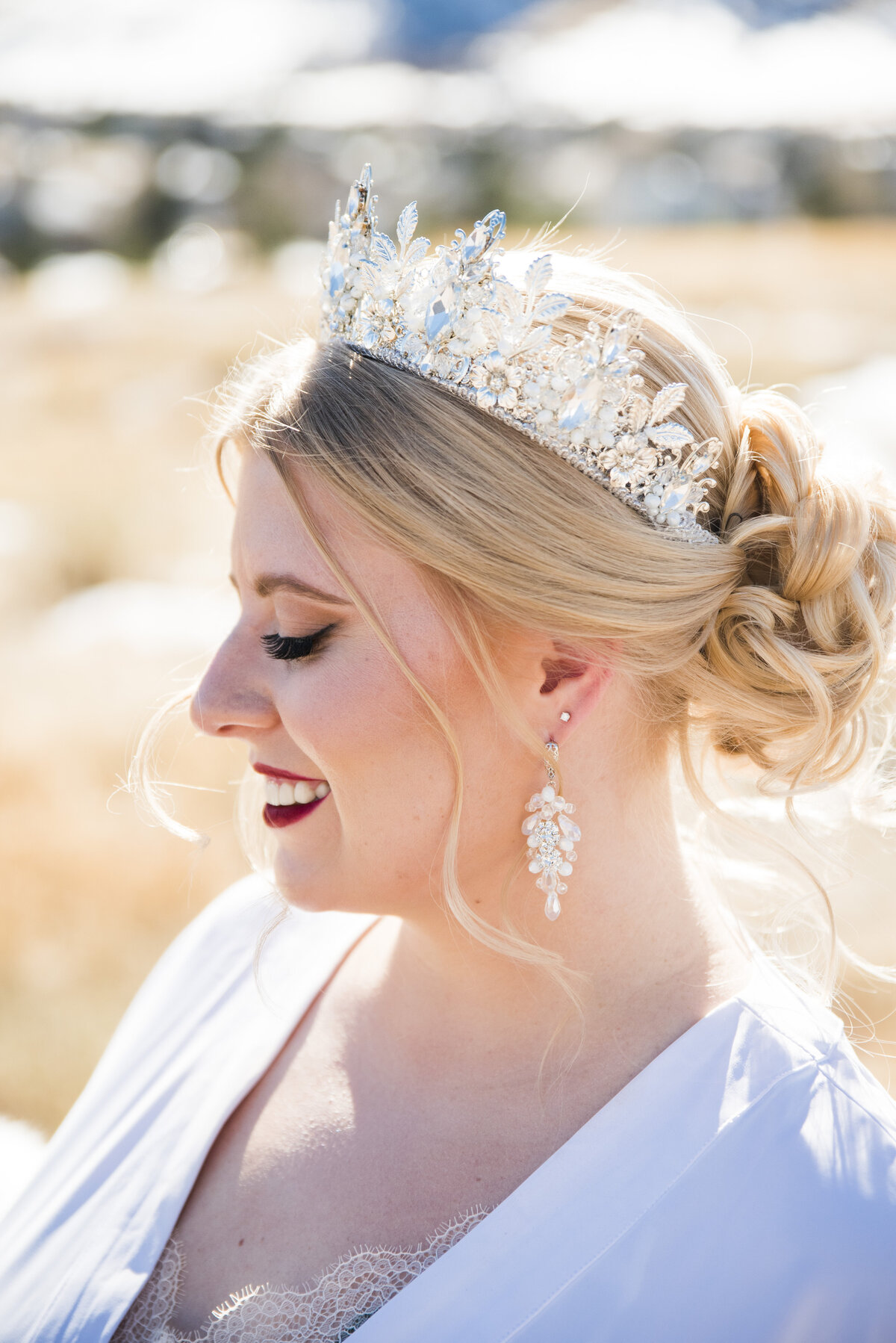 A profile shot of a bride smiling down and wearing a tiara.
