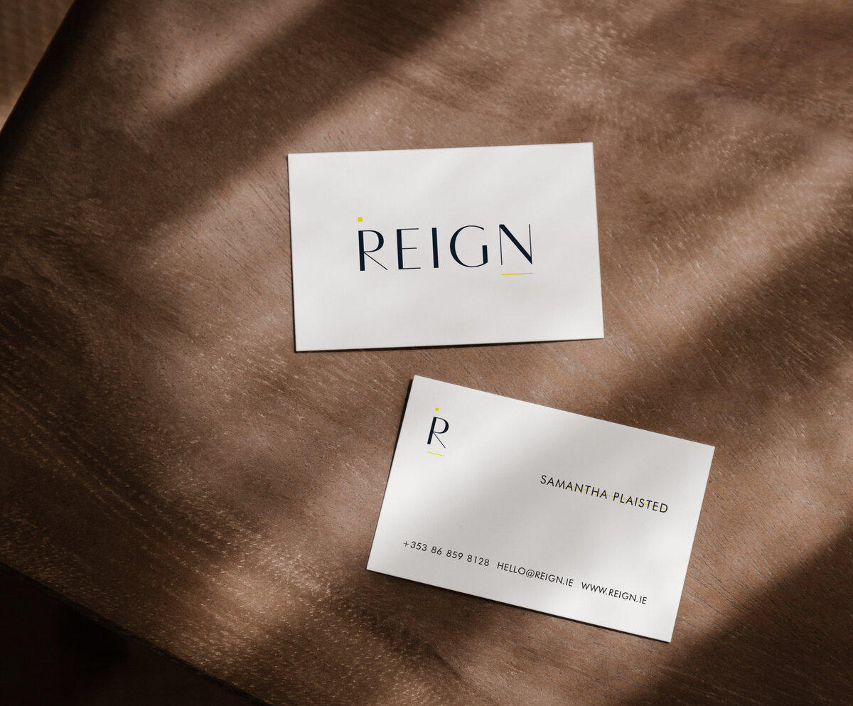 Reign custom business card design for branding project on wood table.