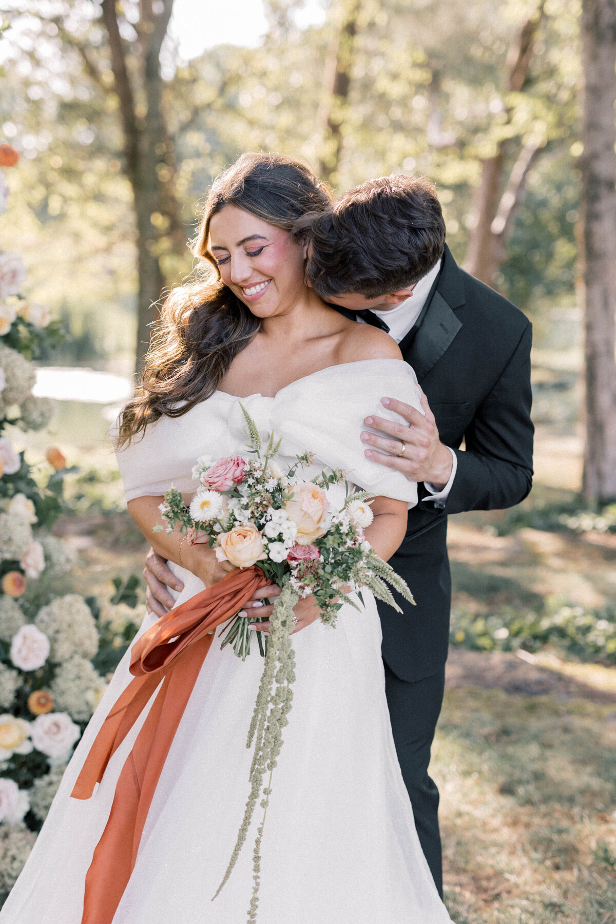 knoxville  bride holding thistle and lace bouquet while being hugged  by groom