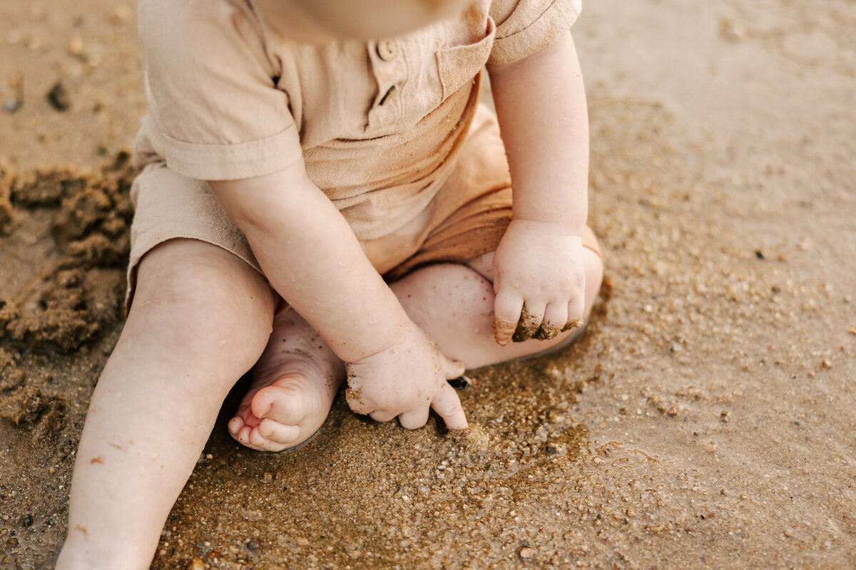 close up of baby boy's toes and fingers while playing in the dirt