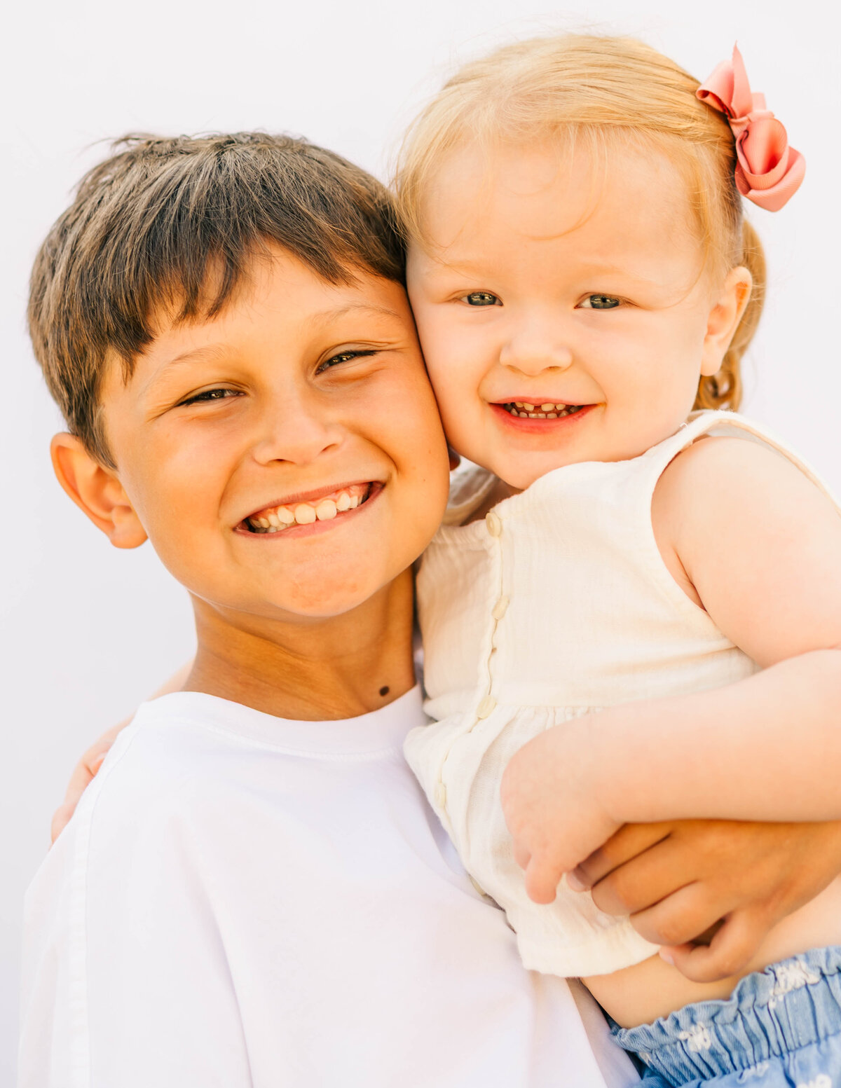 Brother and sister smiling together on white backdrop — fine art sibling portrait by S. Reed Photography