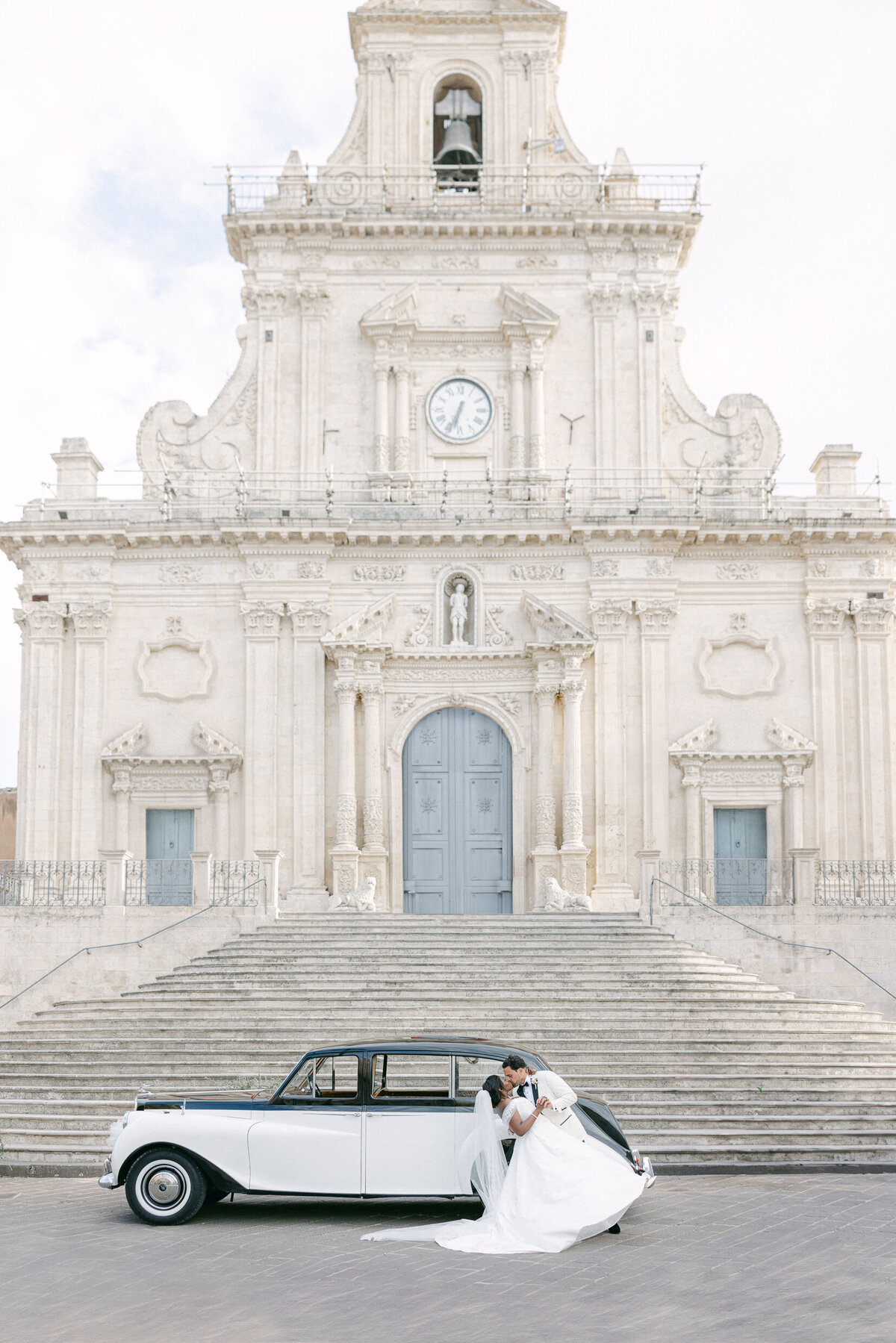 newlyweds kissing in front of a grand wedding venue