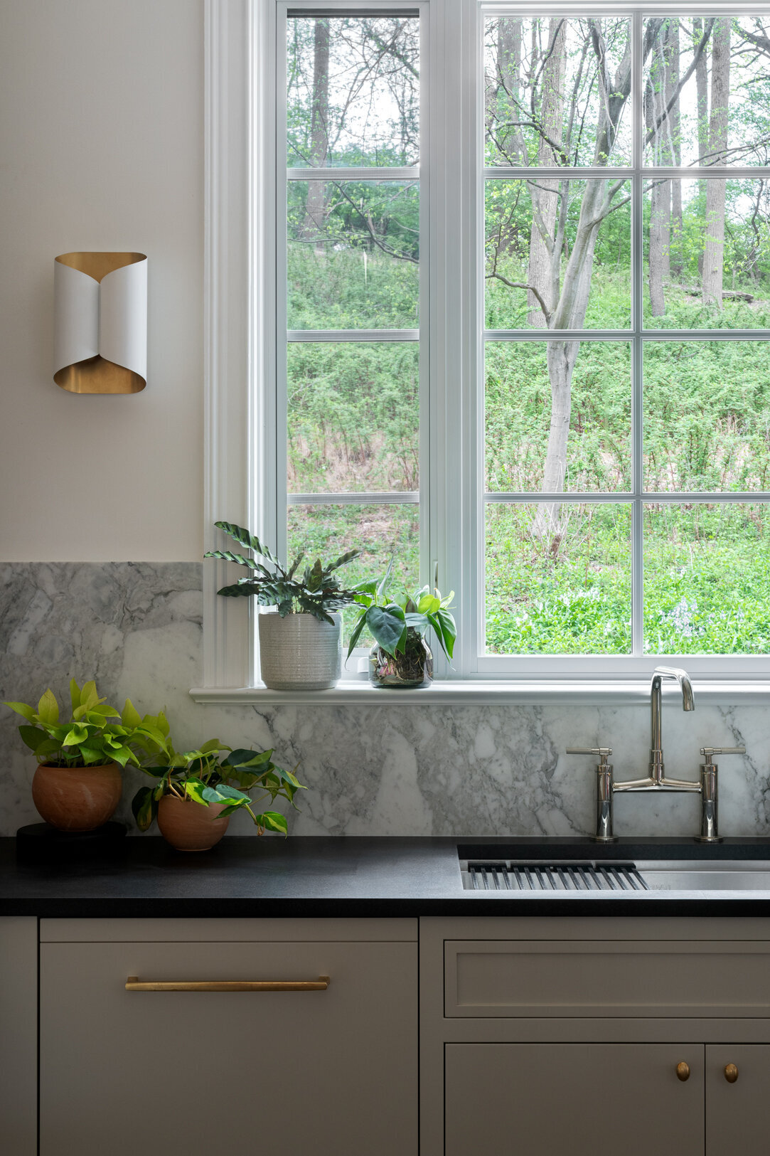 tan cabinets with black countertop, sink and window overlooking grass