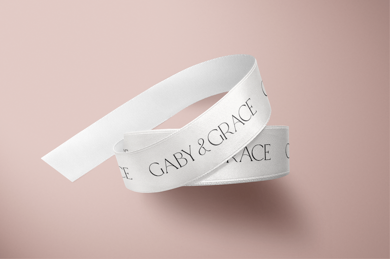 White satin ribbon printed with the Gaby & Grace logo, designed for elegant gift wrapping and elevated brand presentation.