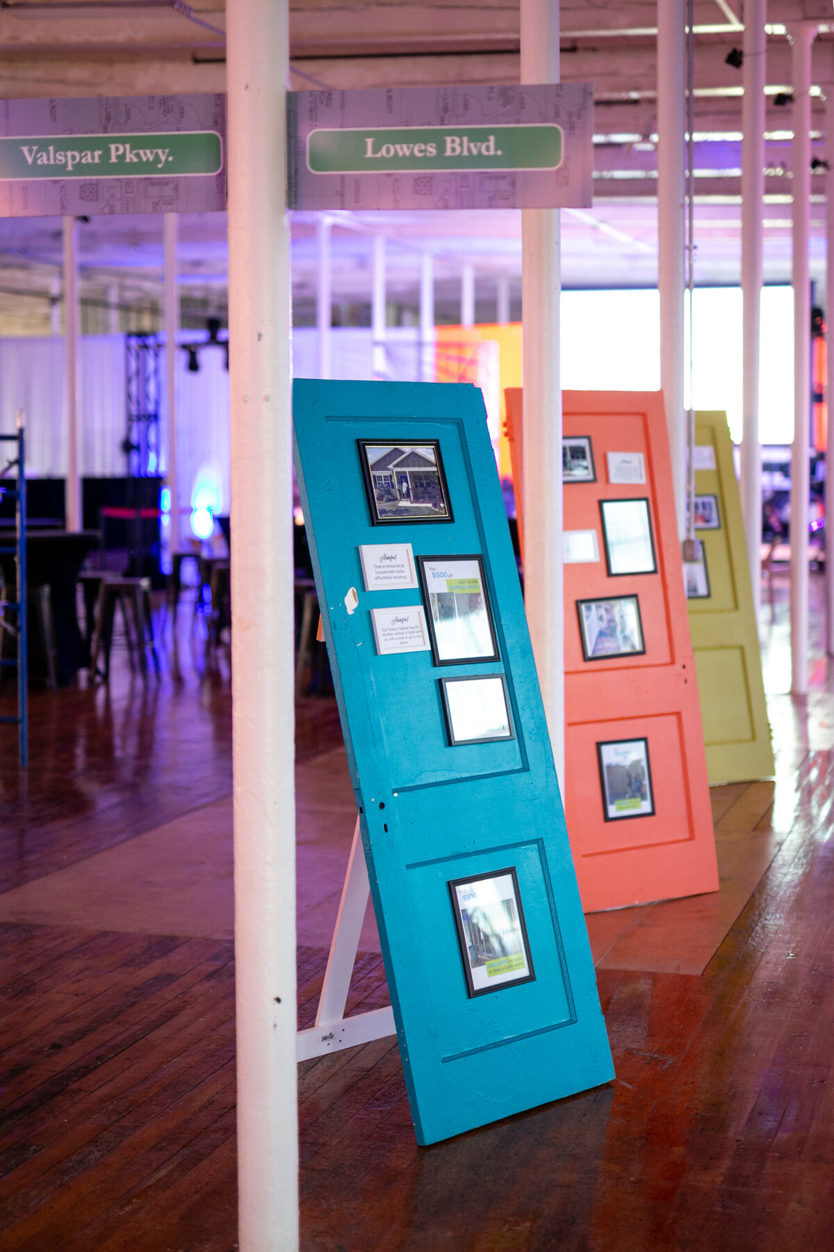 Photos hung on vibrant blue, orange and green doors used as decoration to showcase compelling photography for non-profit event.