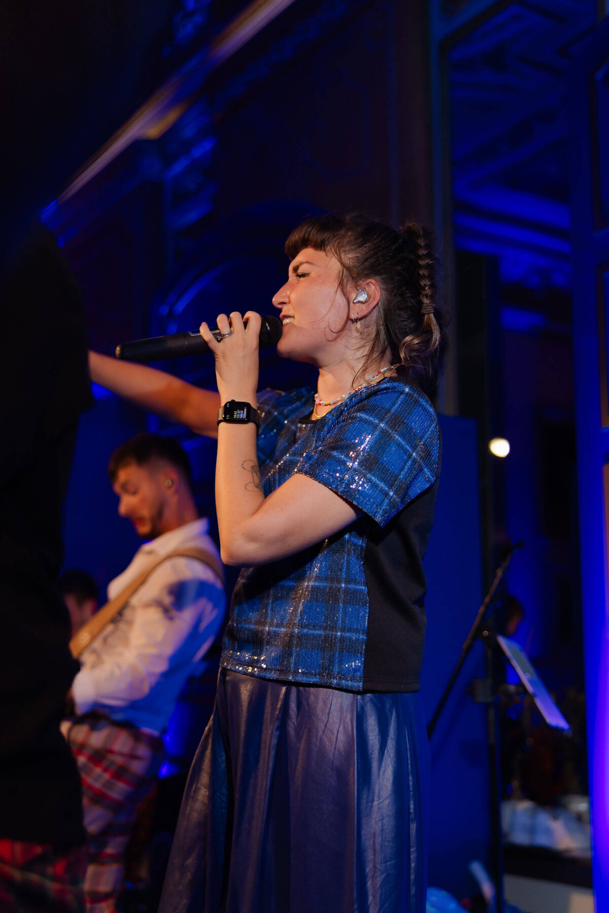 female singer performing on stage in the ballroom which is washed in blue light at avington park for a 50th birthday party