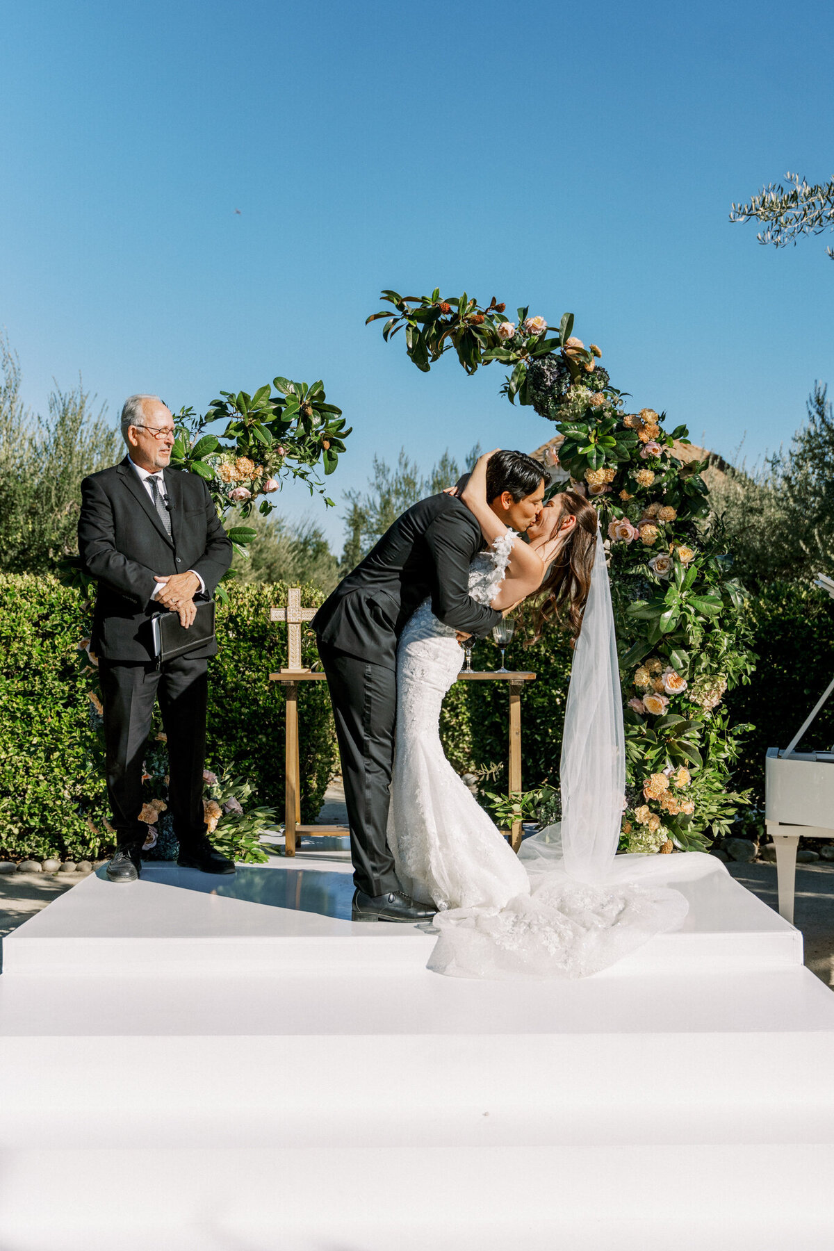 The kiss that sealed forever—bride and groom’s romantic “I do” moment beneath a lush floral arch at Allegretto Vineyard.