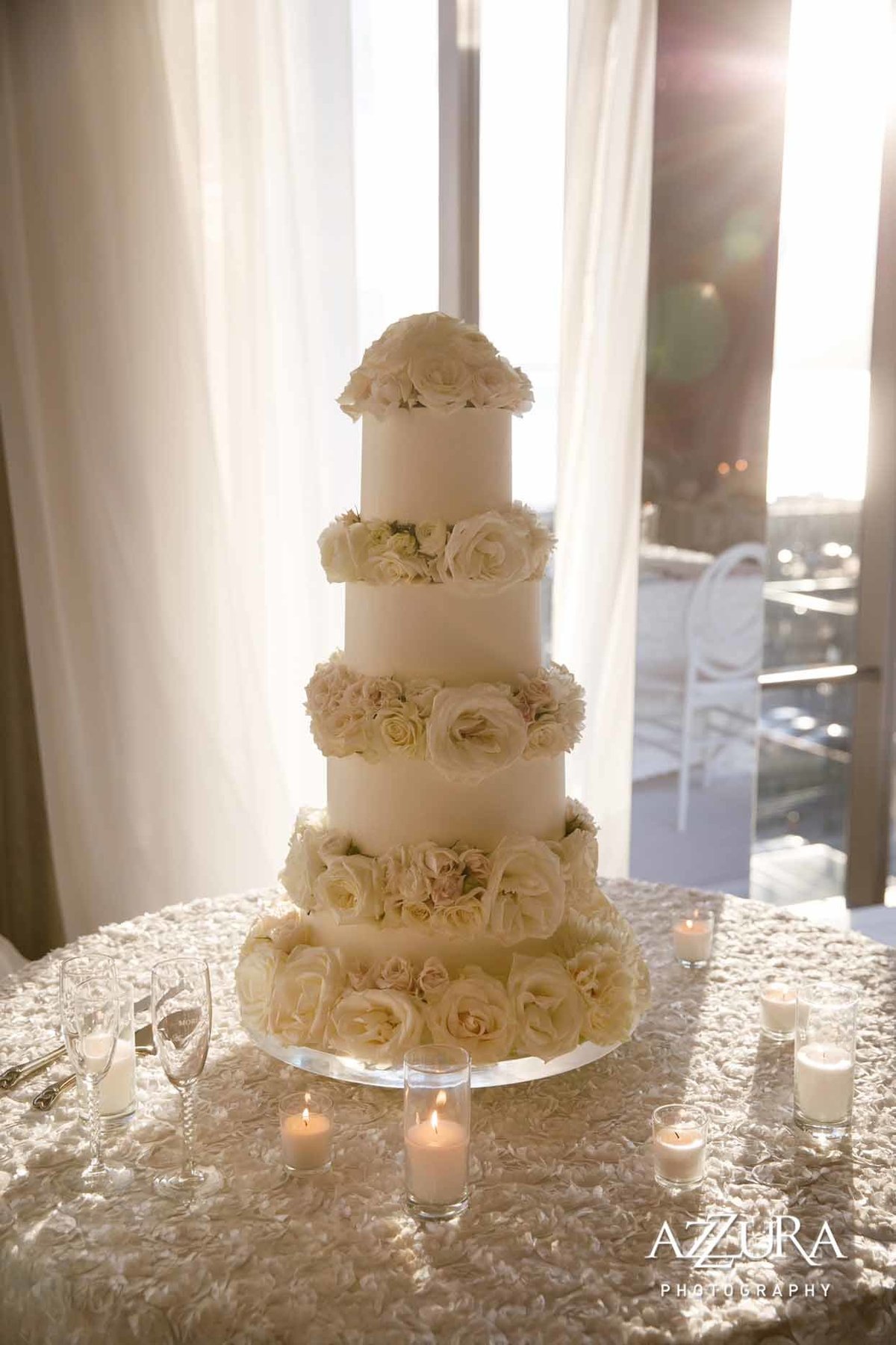 grand wedding cake with white roses on white rose table linens