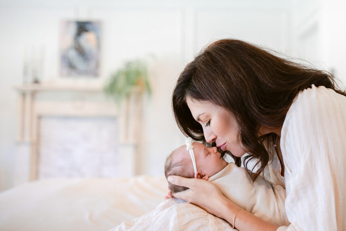 Dunwoody newborn photographer- mom and baby in bed, mom kissing baby, lifestyle newborn photos