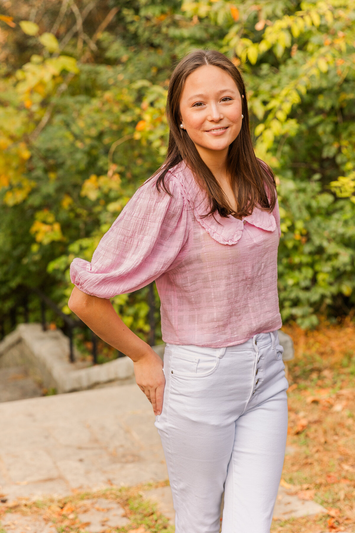 teenager wearing a white jeans and a pink blouse looking at the camera hands in back pockets during lifestyle photoshoot