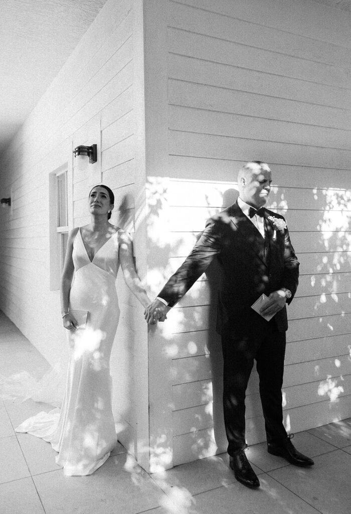 An emotional black and white portrait of the bride and groom holding hands before their wedding, feeling the moment before seeing each other. Destination wedding photography by Claudia Amalia Photography in the Florida Keys.