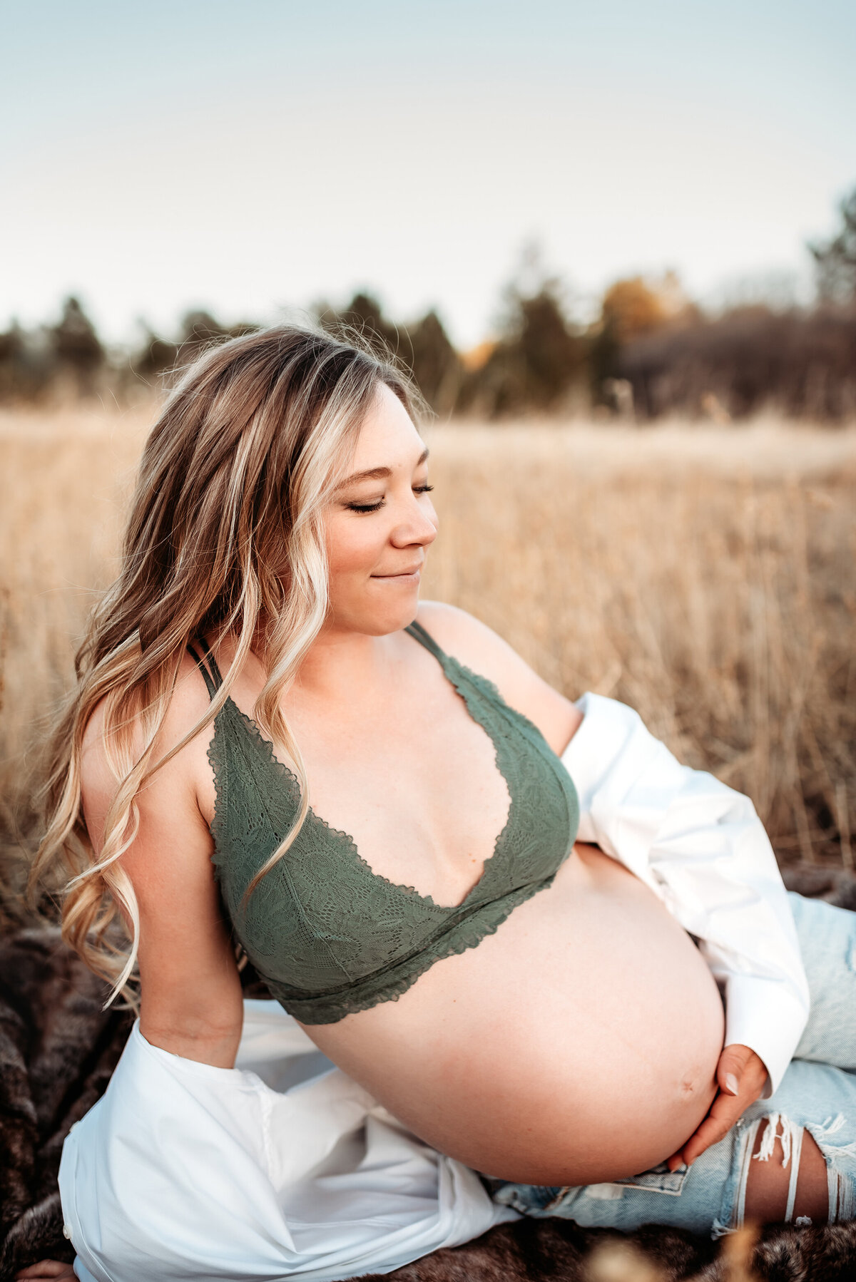 pregnant woman in bra sitting in field