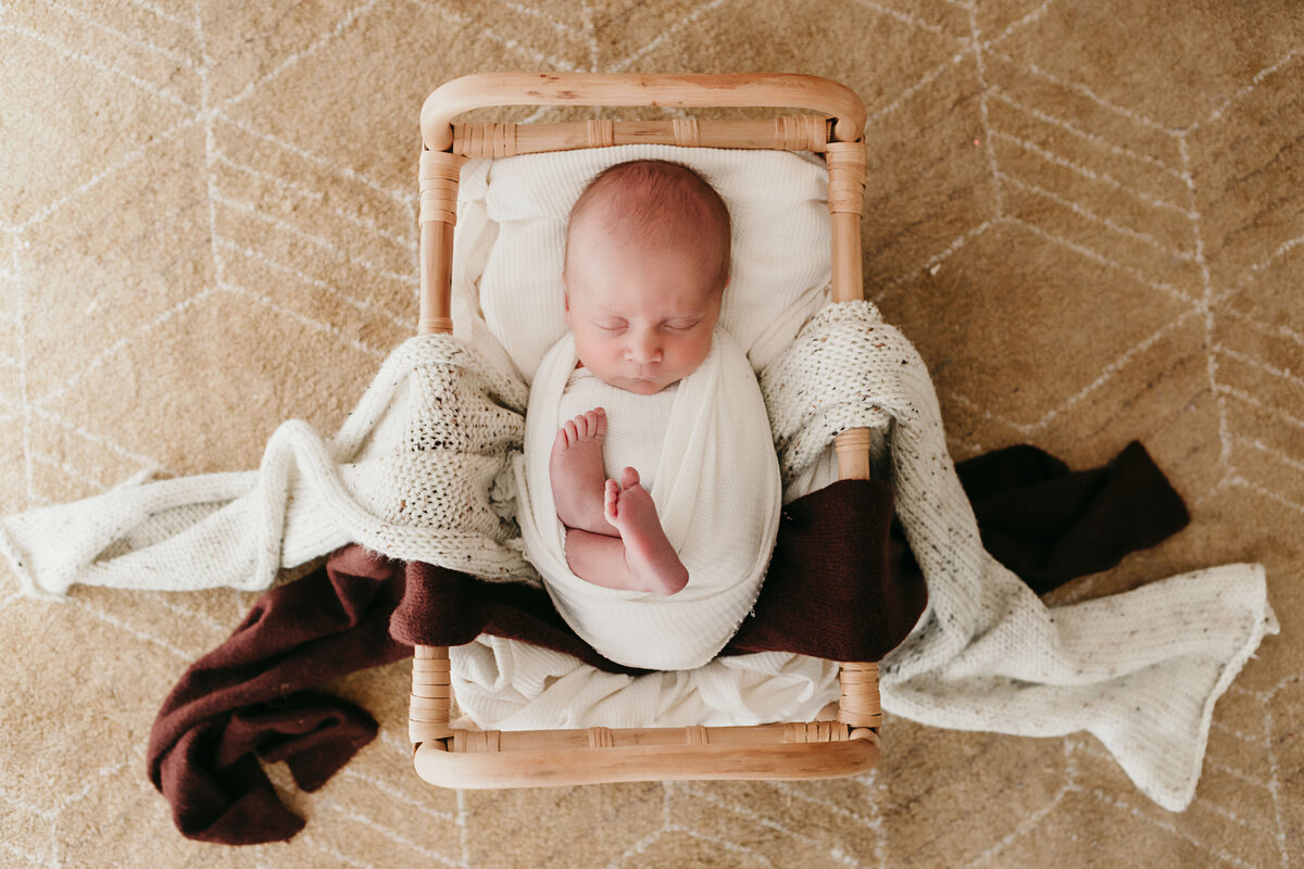 wrapped newborn with feet out posed on bed