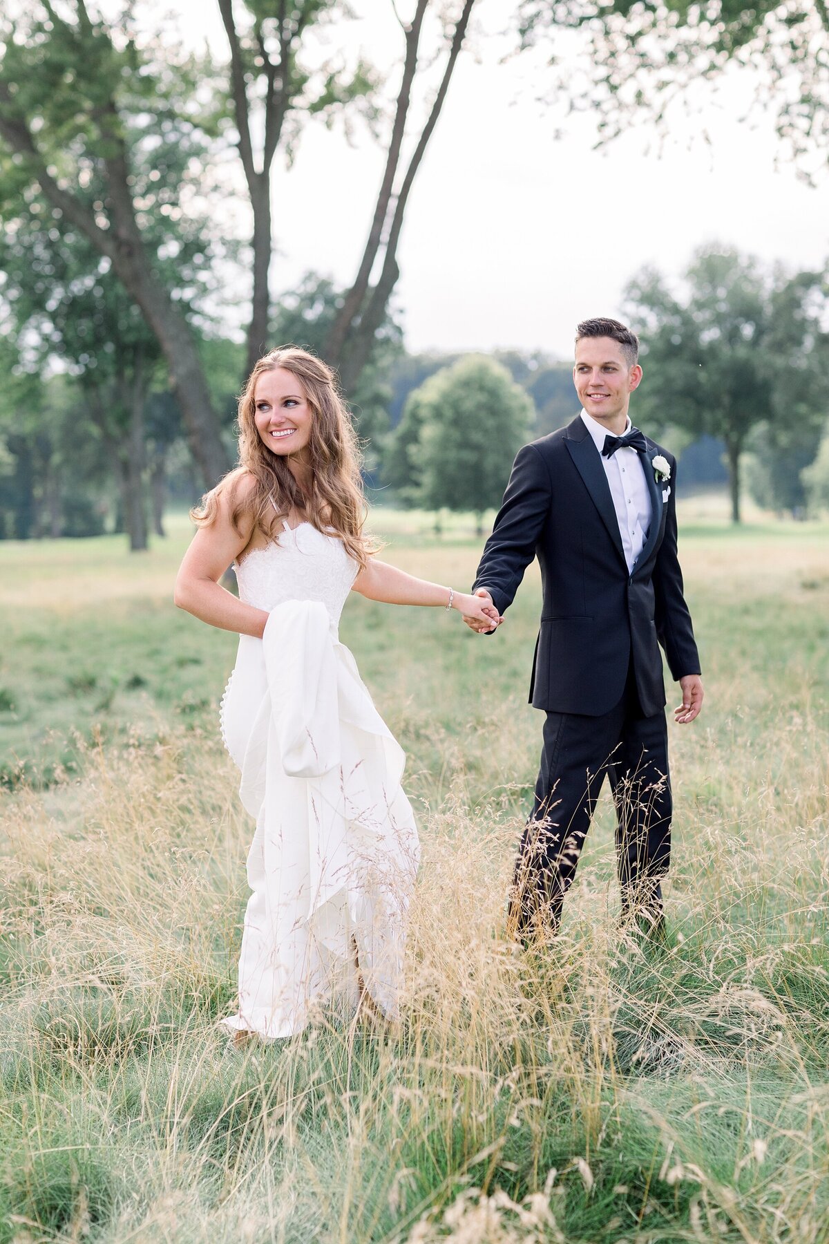 bride and groom walking in field