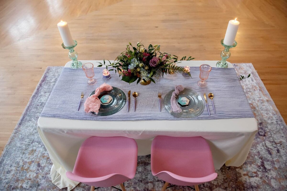 a sweetheart table with vinyl records as chargers and pink chairs at The Evergreen venue