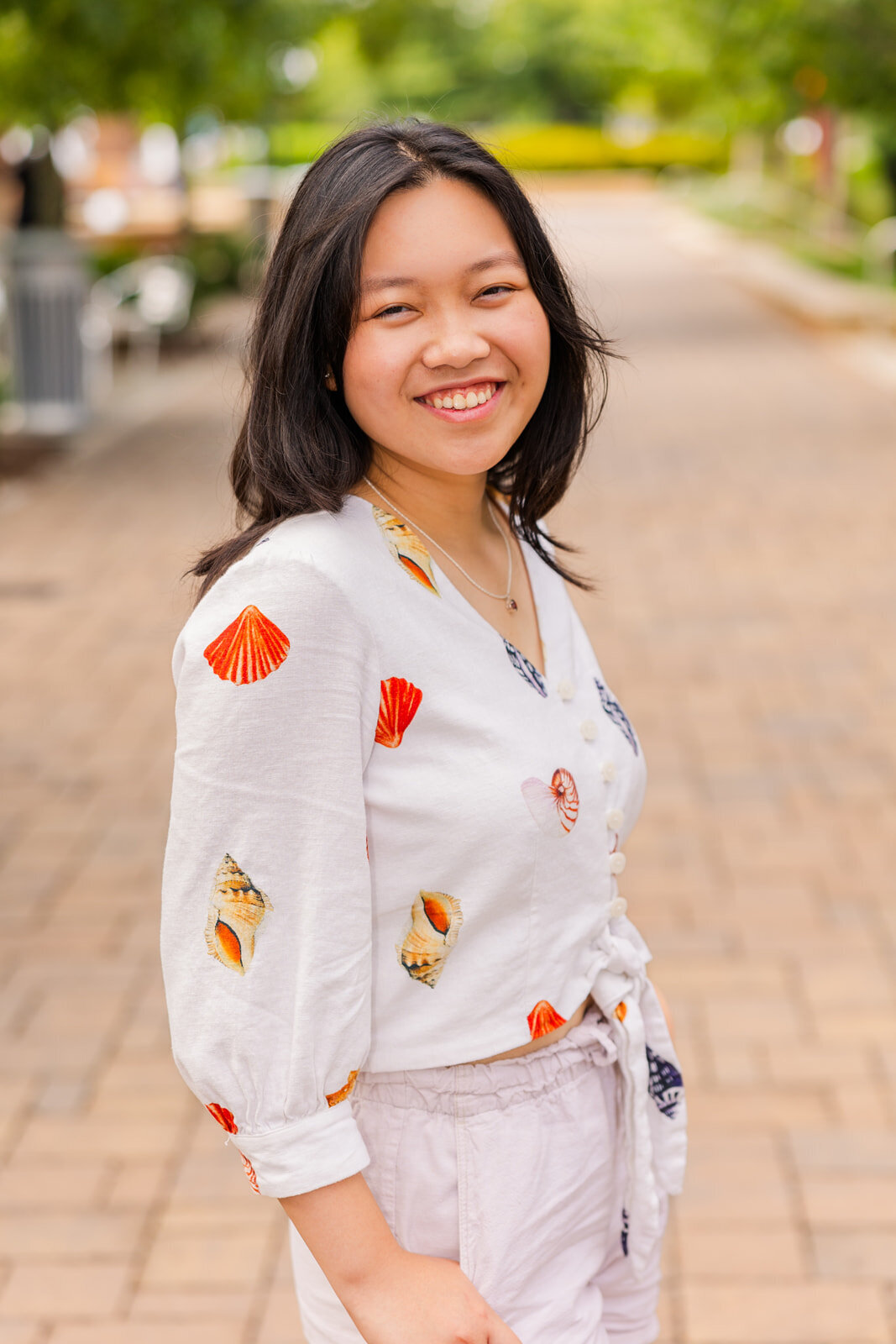 senior girl looking sideway to the camera hands in pocket with a city background vibe in Sandy Spring