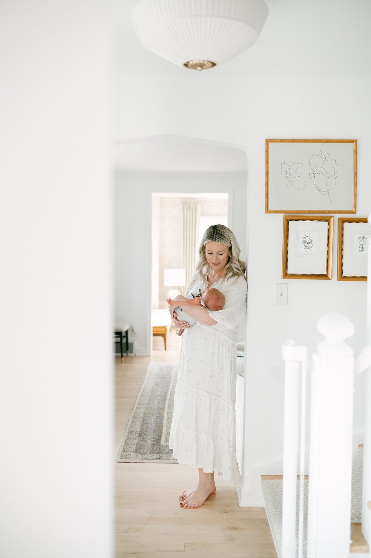 Pulled back image of mom leaning against a wall holding her baby