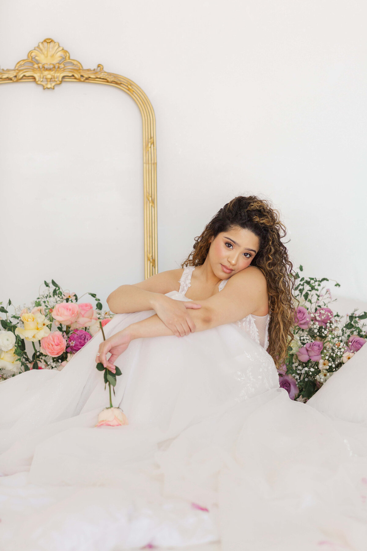bridal portrait sitting in front of gold mirror and roses