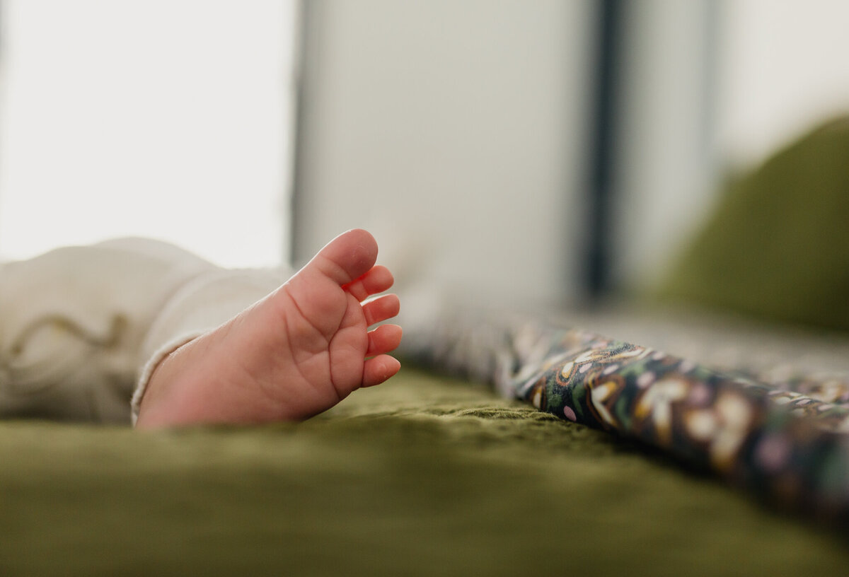 Newborn baby sleeping in bed, feet and toes showing.