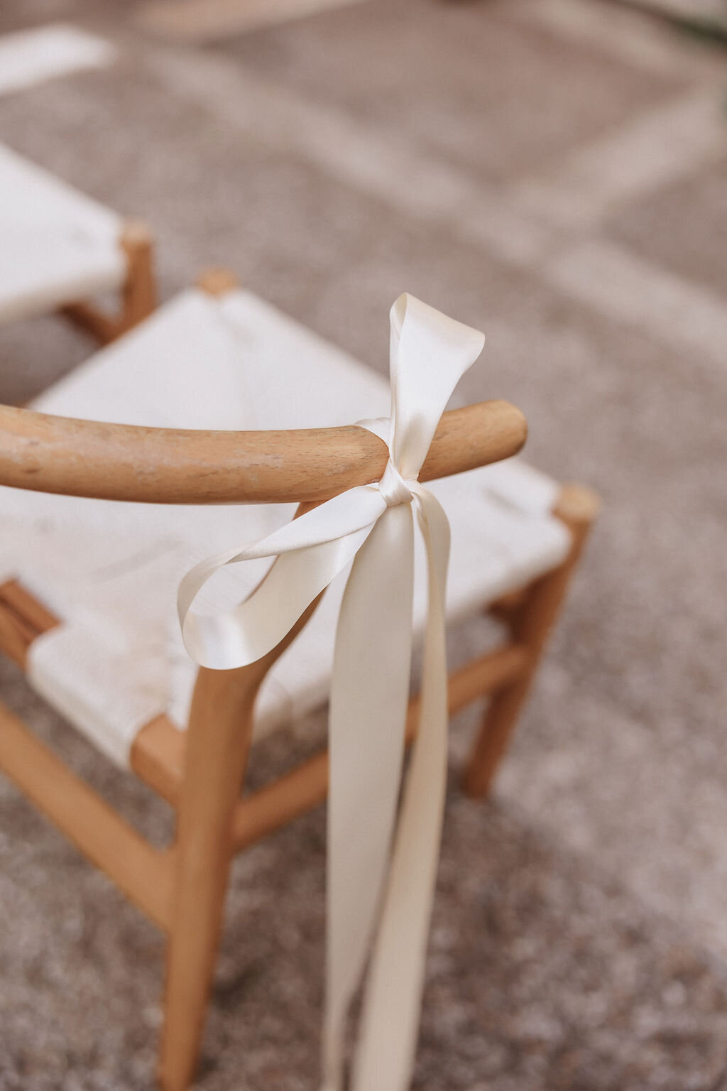 Close up of wishbone chair with ivory ribbon tied to it