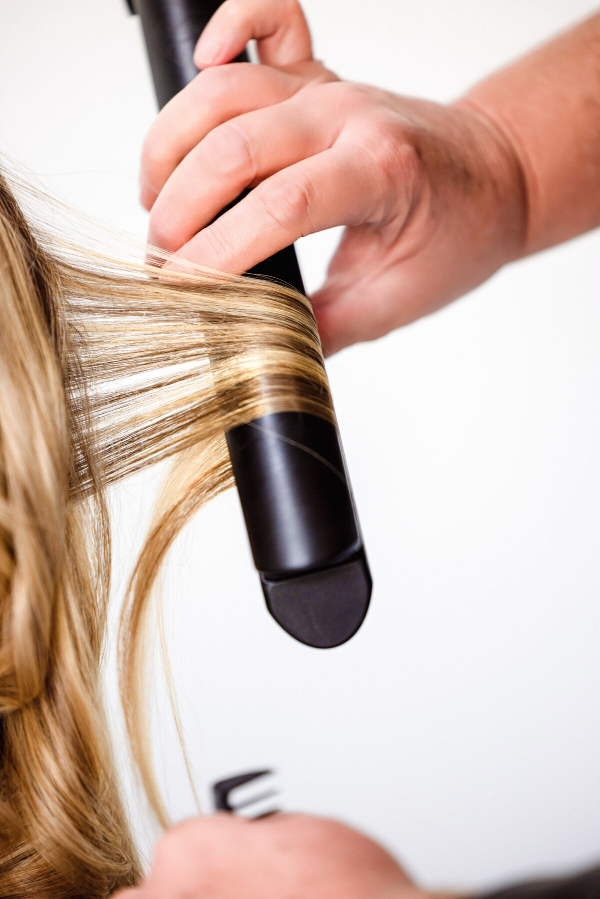 A stylist perfects a client’s hair using a professional curling iron, adding bounce and body to her locks. This image radiates confidence and elegance, ideal for promoting high-end styling services.
