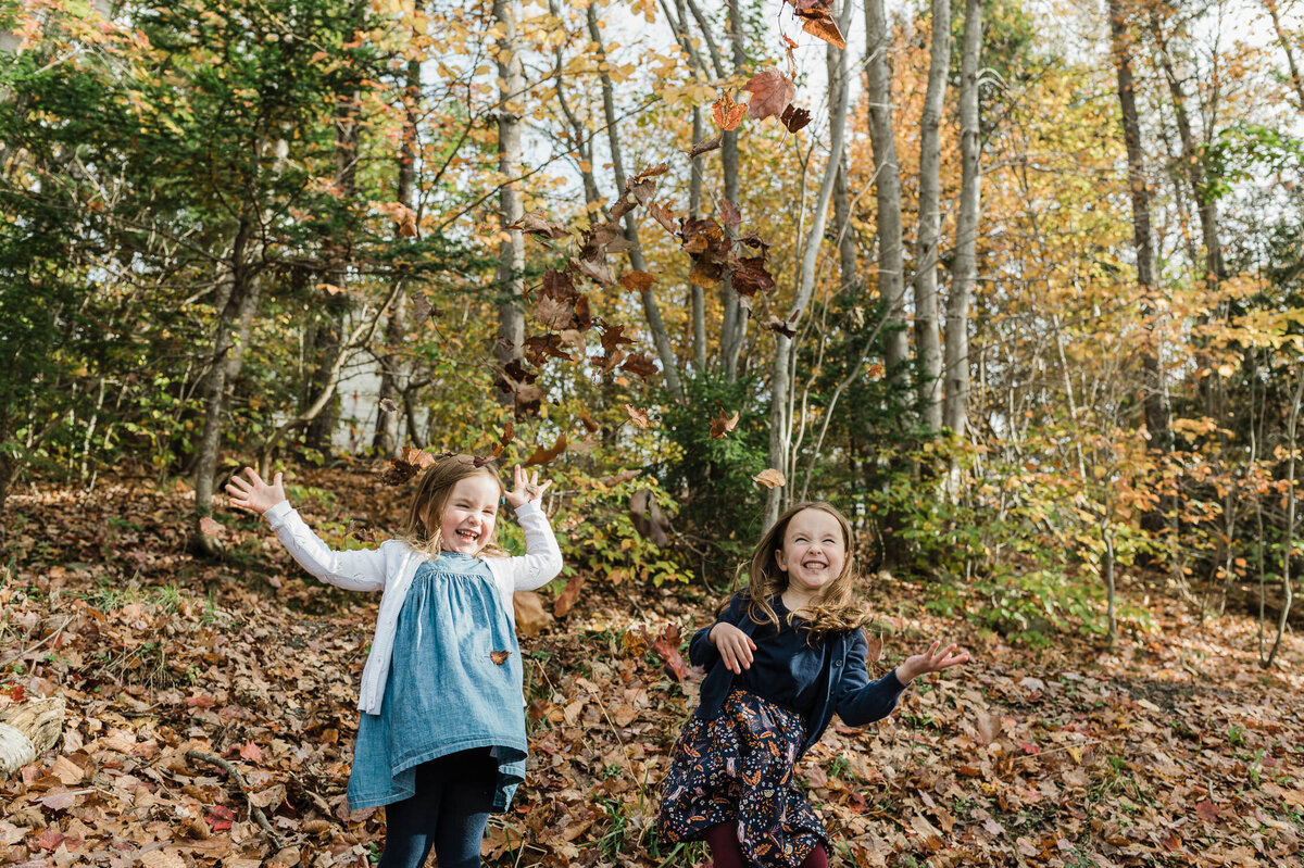 Kids playing in fall leaves.