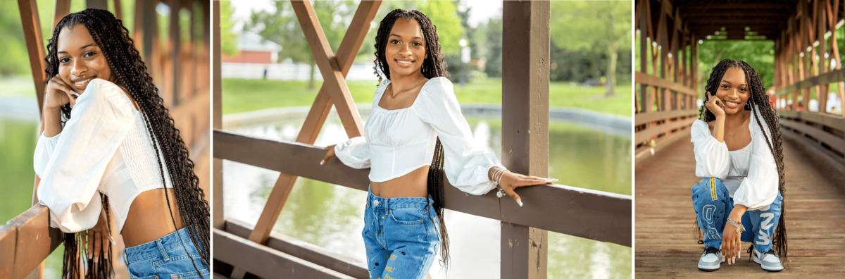 African American senior girl wearing a white princess sleeve blouse, decorated blue jeans, and gray and whie Nikes squatting on a bridge