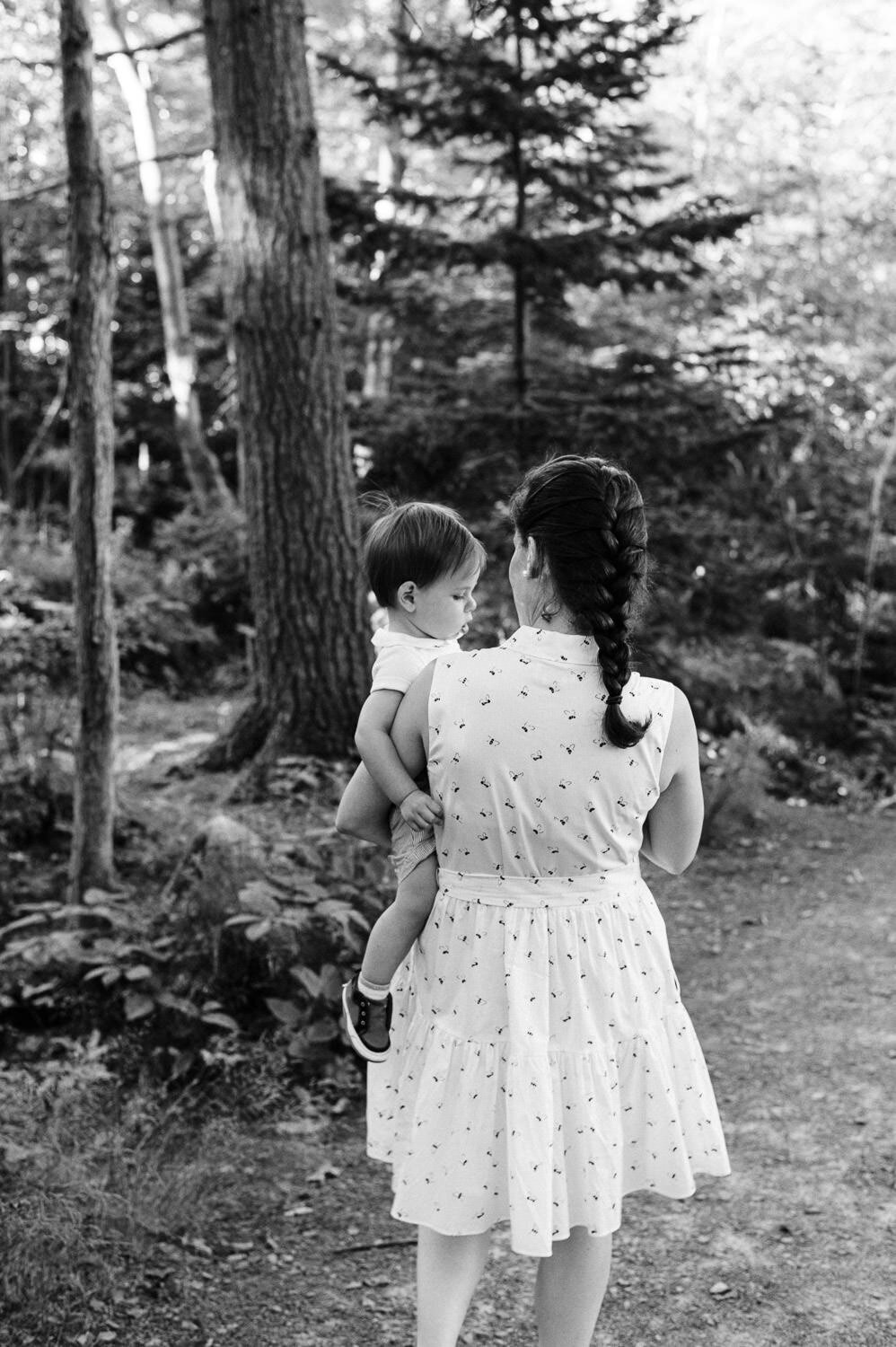 Woman holding toddler in the forest.