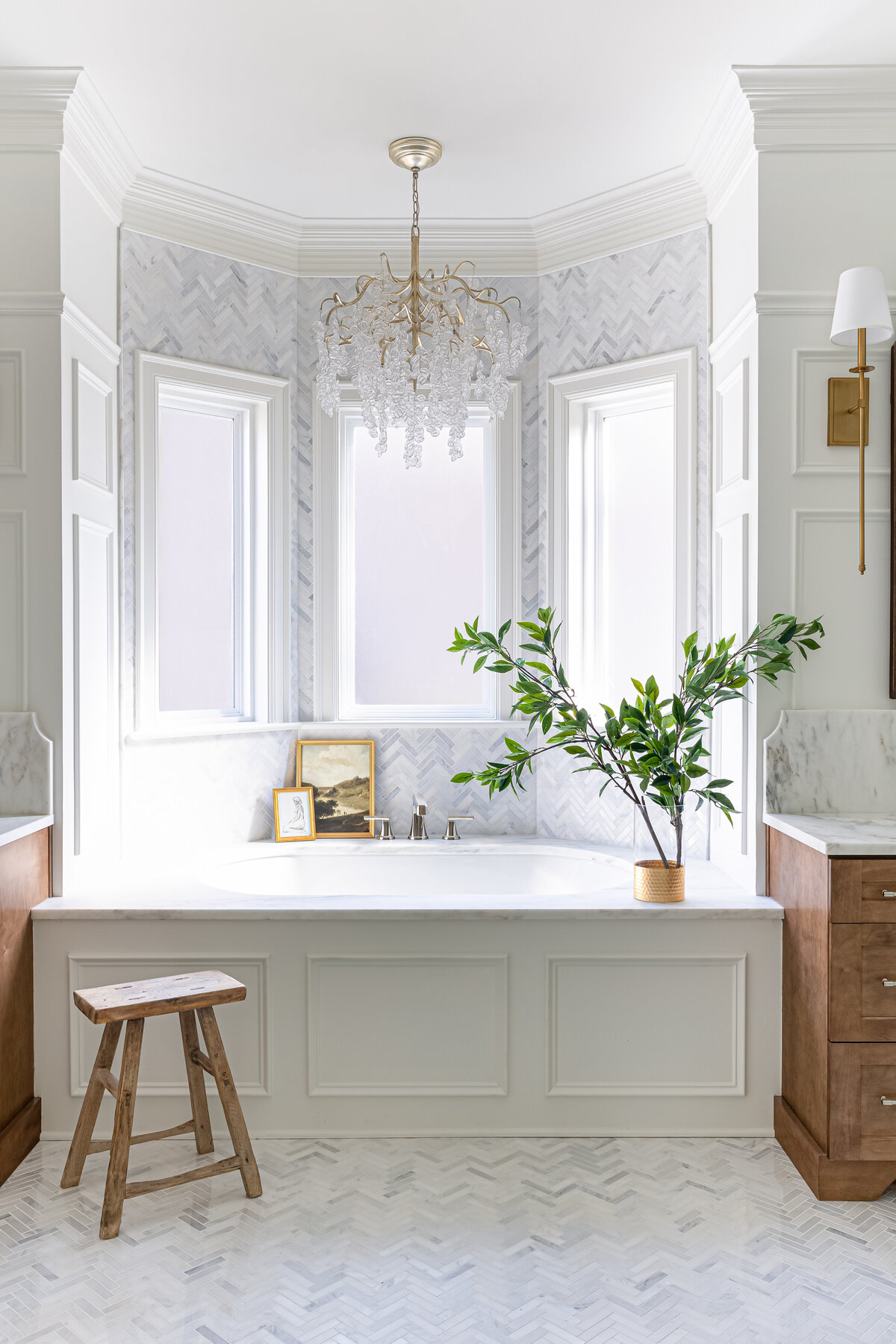 Primary traditional bathroom with herringbone tile flooring and a chandelier.