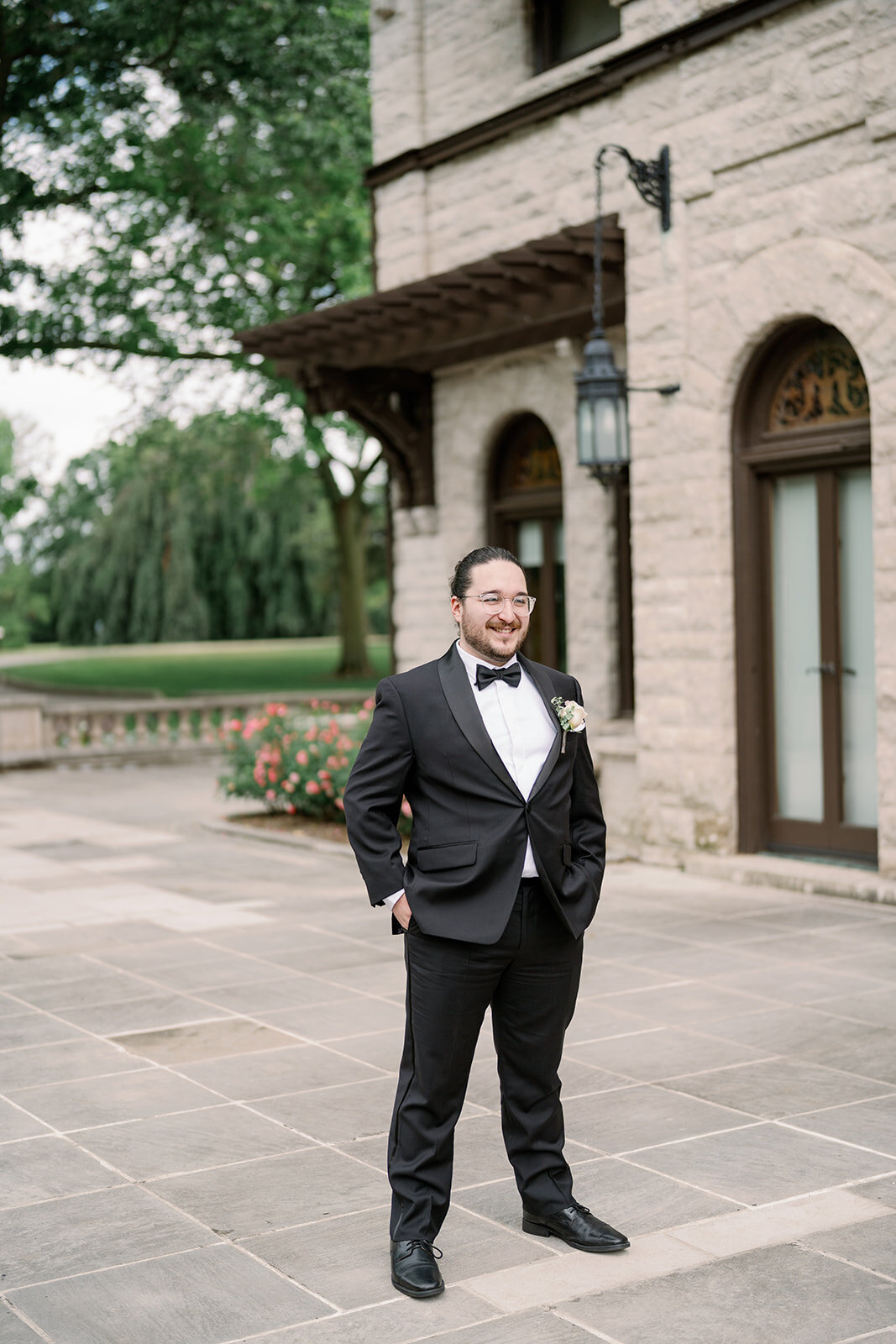 Groom standing outside the Henry Ford Estate in Dearborn Michigan wearing a classic black tuxedo, photographed by a Michigan wedding photographer.